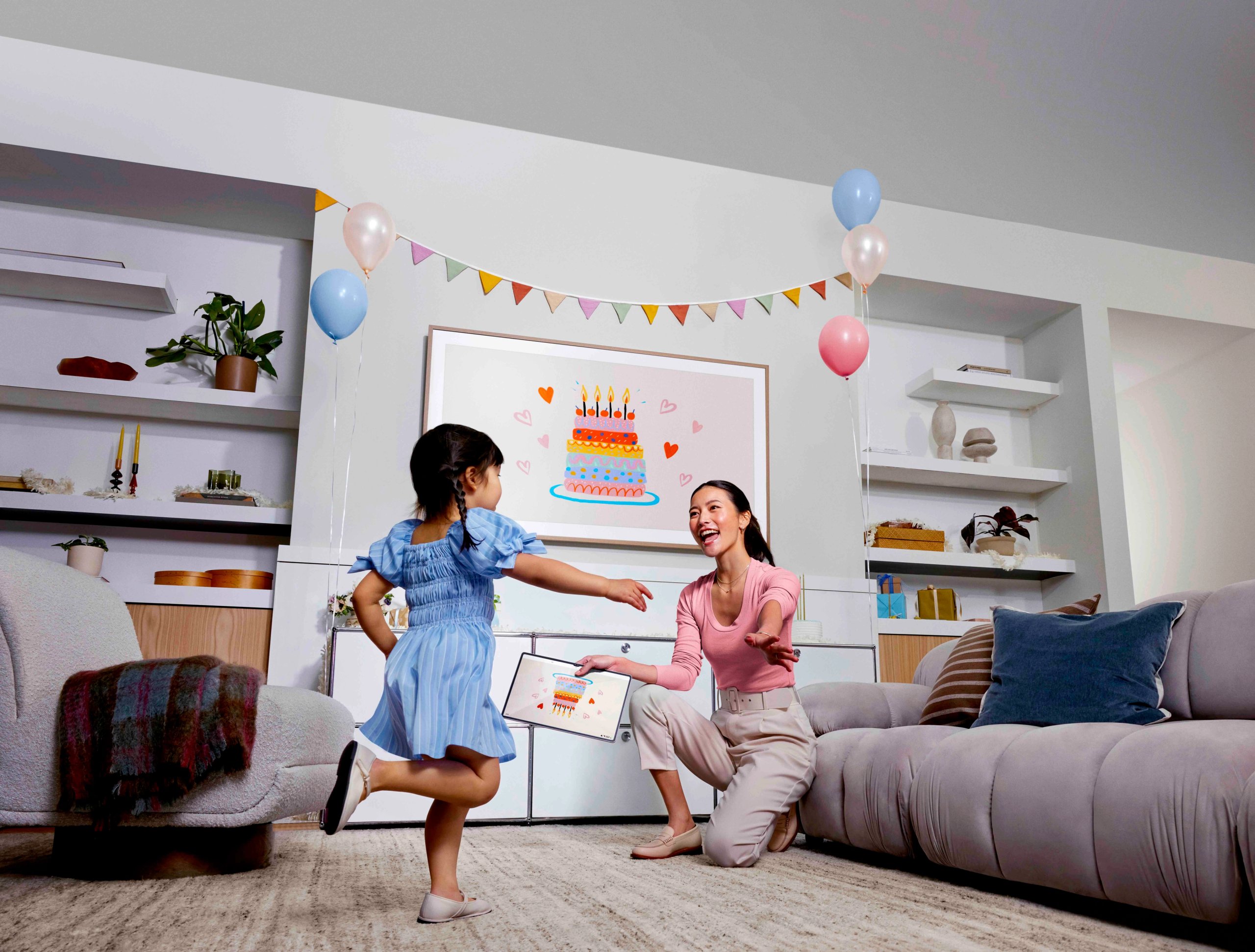 Mother and daughter celebrating birthday with Samsung Frame TV displaying cake artwork