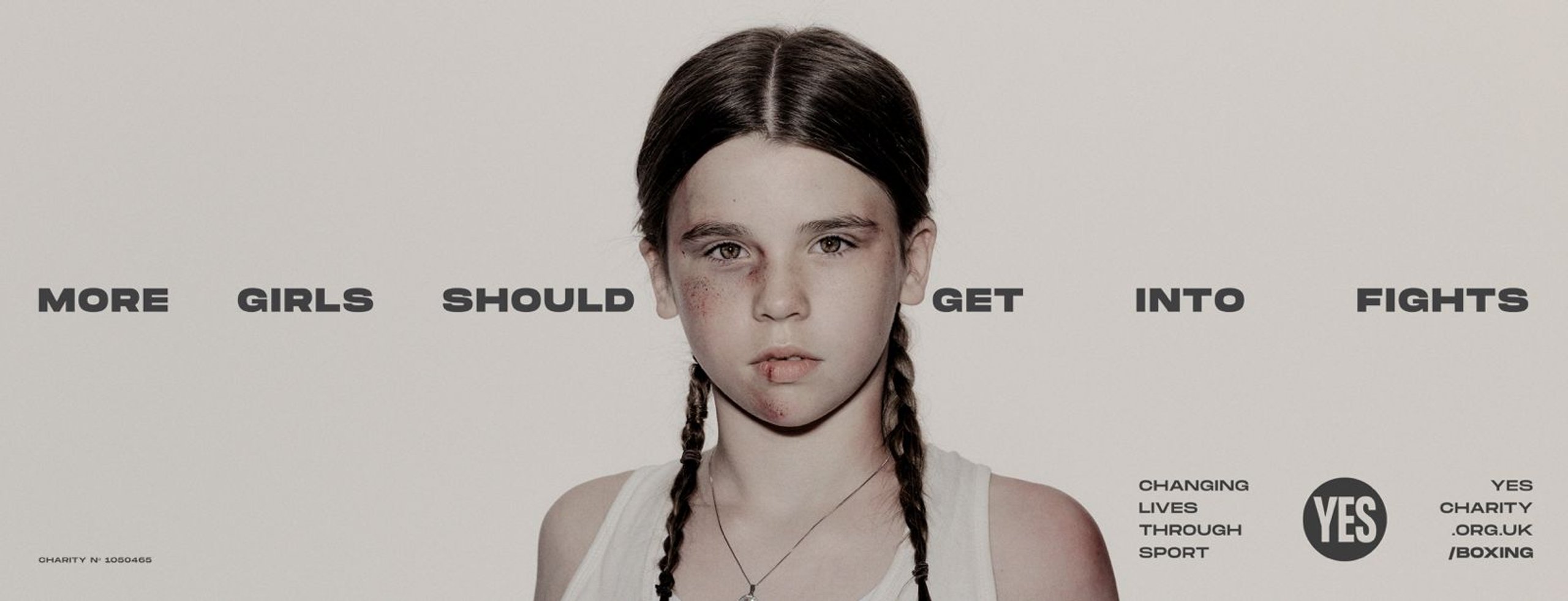 Young girl boxer with braids and bruised face in YES! More Girls Should Get Into Fights campaign