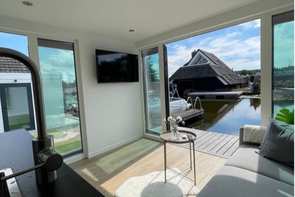 Vanuit de fraai ingerichte woonkamer hebben de bewoners direct uitzicht op het water.