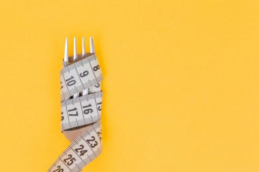 fork wrapped in measuring tape - 500-Calorie Meals For Weight Loss