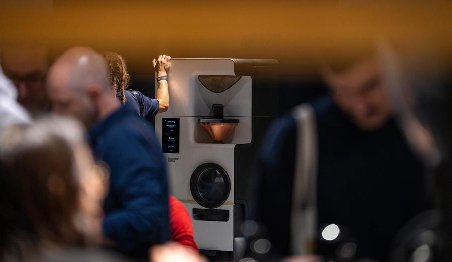 An attendee leans over the Bellwether Shop Roaster mid-preheat as an audience gathers around it at the An Evening with James Hoffmann event in Dubai.