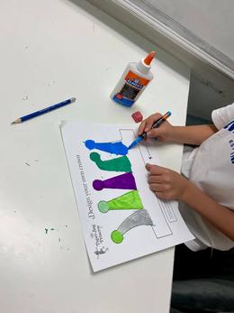 A child painting a "Design your own crown" activity sheet from The Paper Bag Princess in blue, green and purple.