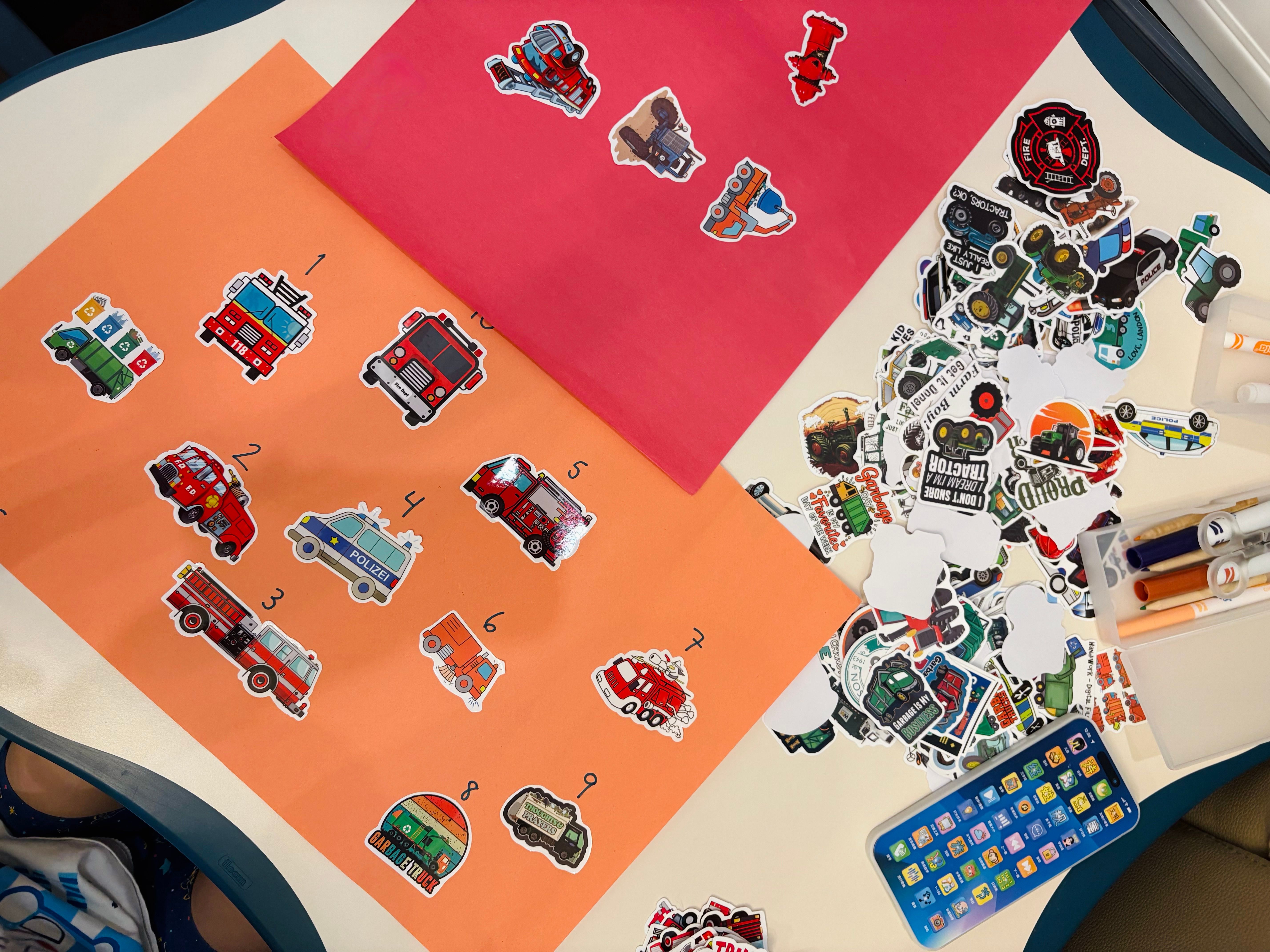 Numbered fire-truck and rescue-vehicle stickers arranged on coloured paper for a counting activity.