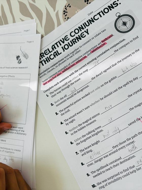 A child filling in a correlative-conjunctions worksheet in pencil, beside a reading-comprehension page on food science.