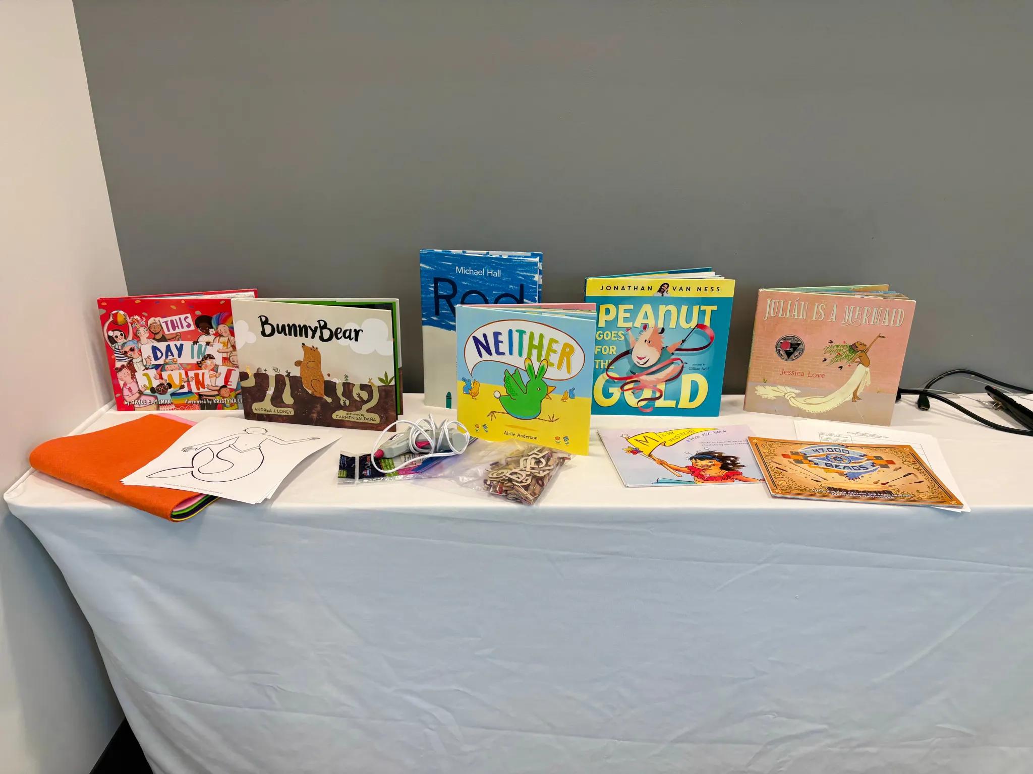 A table set up for circle time with 2SLGBTQIA+-affirming picture books and craft supplies.