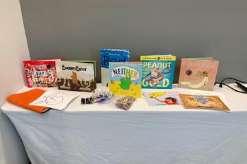 A table set up for circle time with 2SLGBTQIA+-affirming picture books and craft supplies.