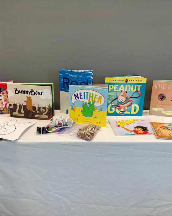 A table set up for circle time with 2SLGBTQIA+-affirming picture books, a colouring sheet, and craft supplies.