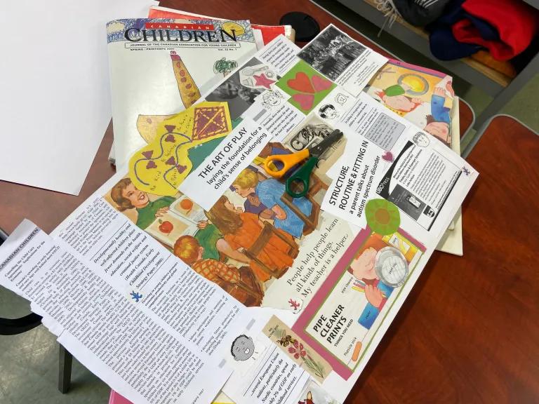 Early childhood teaching resources spread across a table, including an issue of the journal Canadian Children and a handmade collage about the art of play.