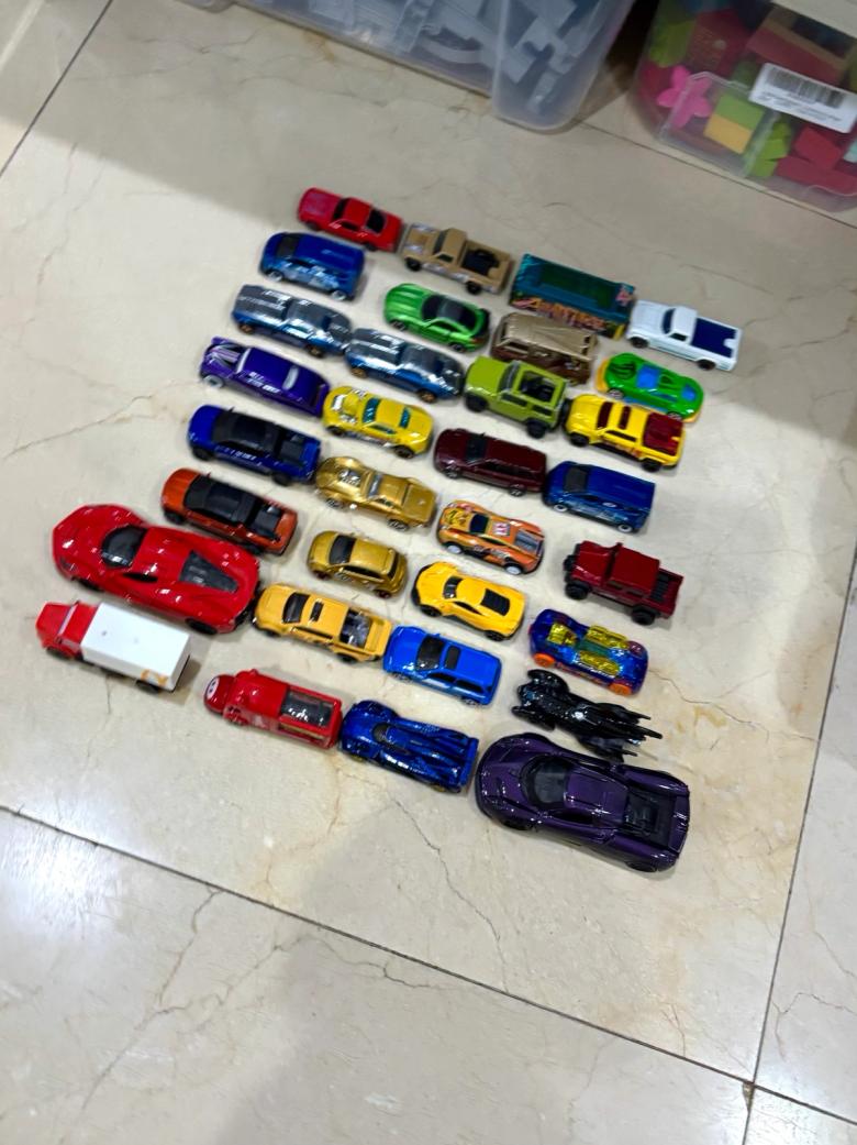 Around thirty toy cars arranged on a tiled floor in even rows, so they can be counted as equal groups.