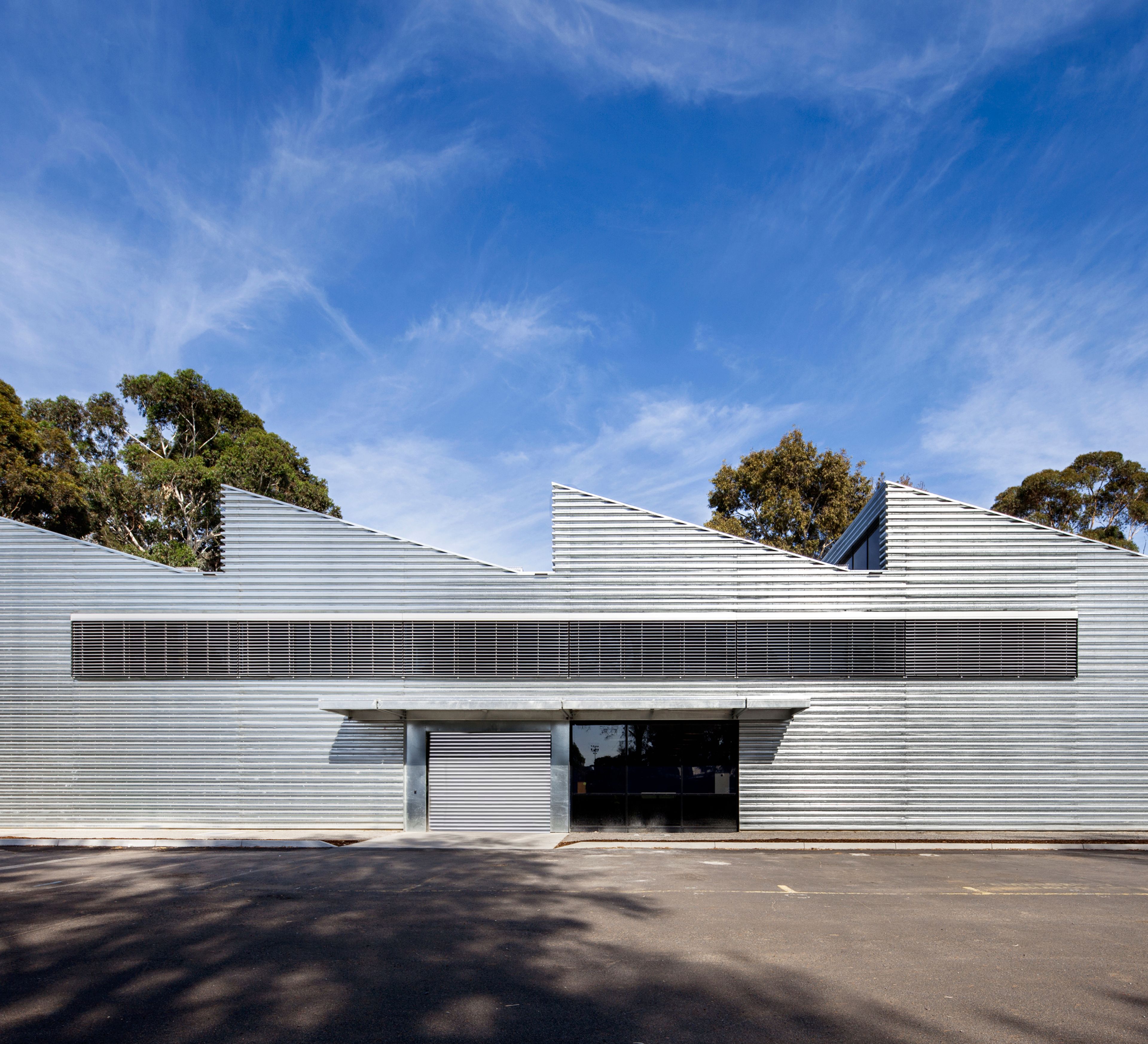 Monash University Building 56 at Clayton Campus, a sustainable adaptive reuse project by McGlashan Everist featuring corrugated metal cladding and sawtooth roof forms.