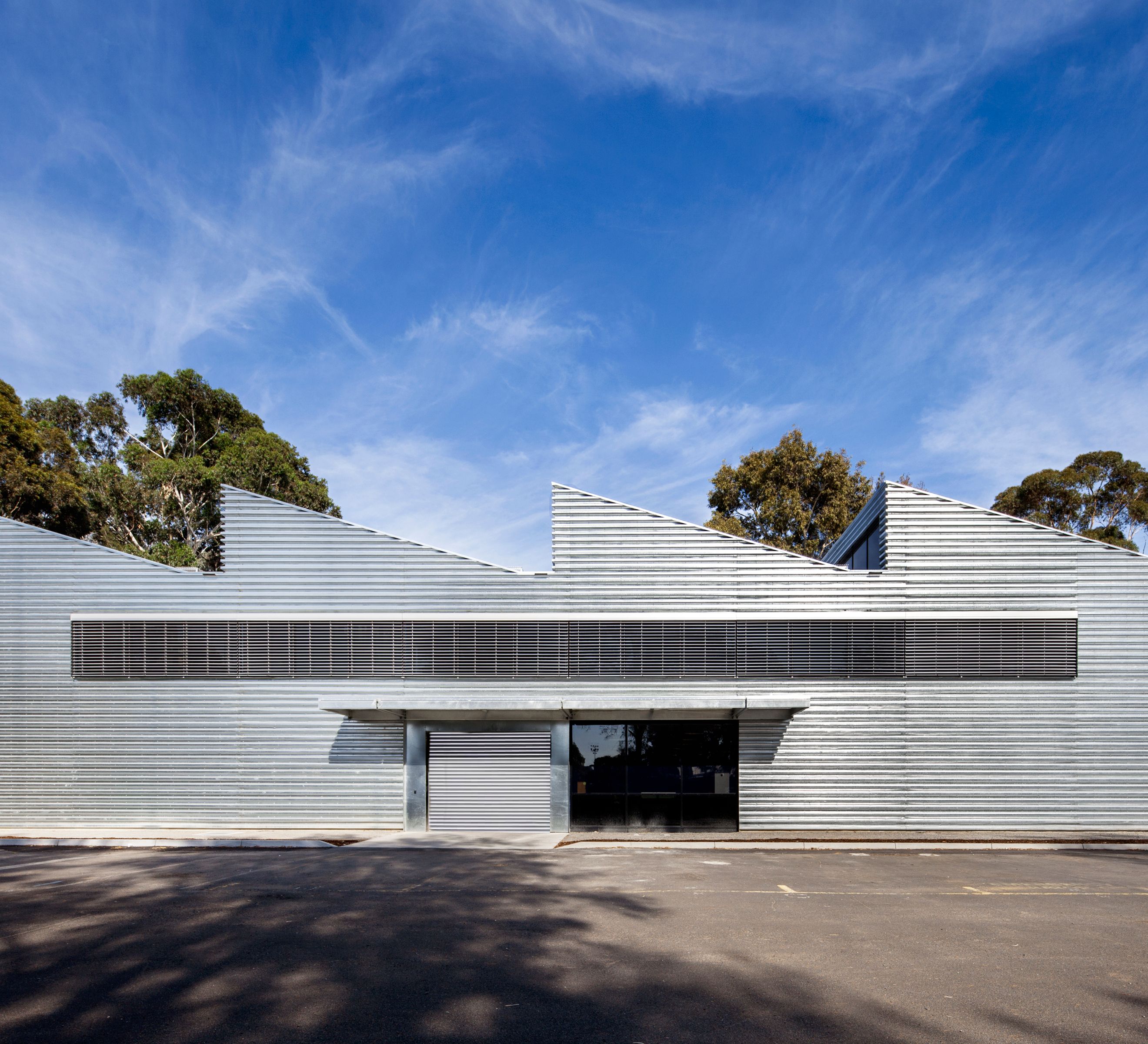 Monash University Building 56 at Clayton Campus, a sustainable adaptive reuse project by McGlashan Everist featuring corrugated metal cladding and sawtooth roof forms.