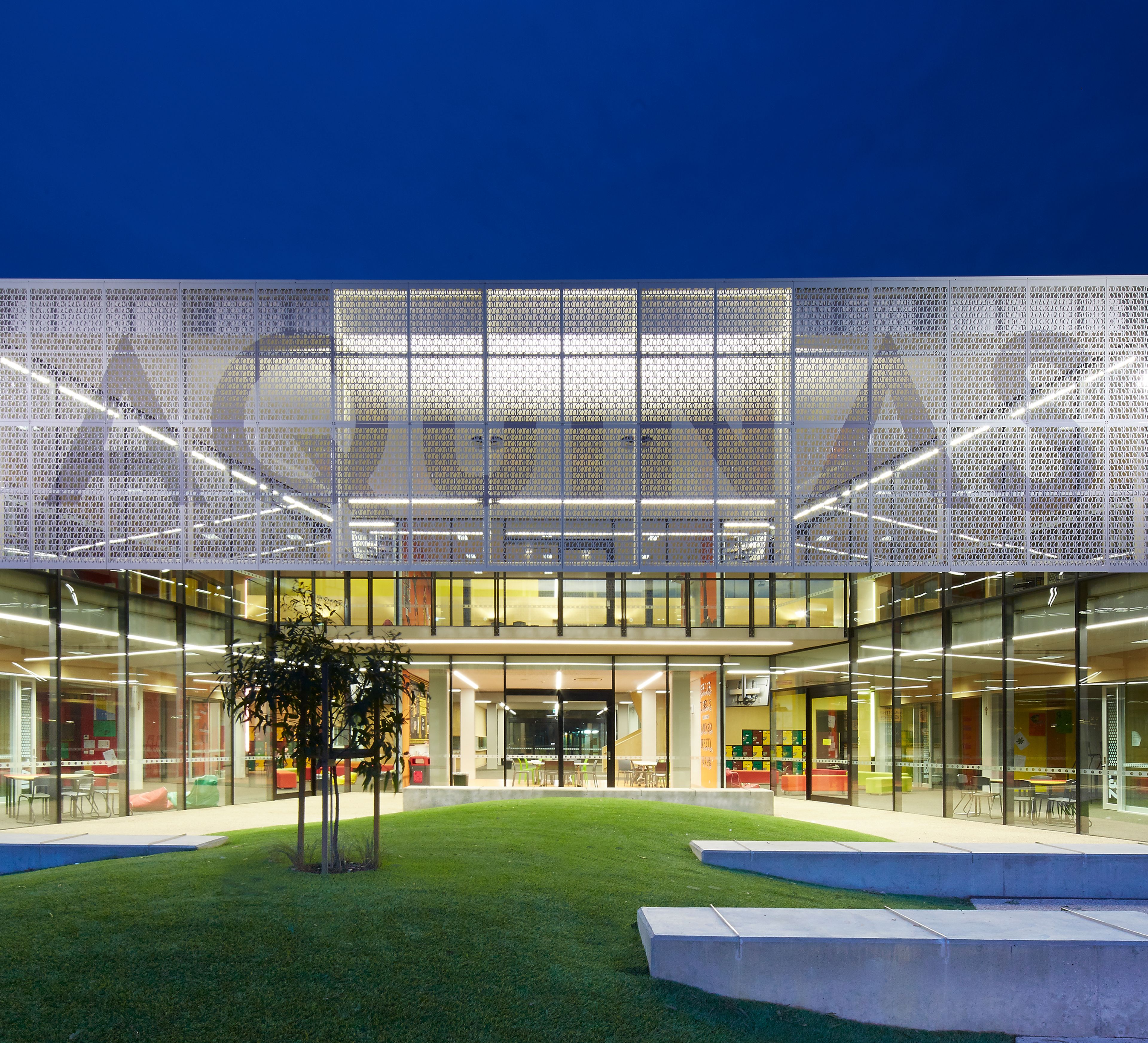 Aquinas College learning courtyard with glazed classrooms, landscaped outdoor space and perforated metal façade screen designed by PMDL McGlashan Everist.