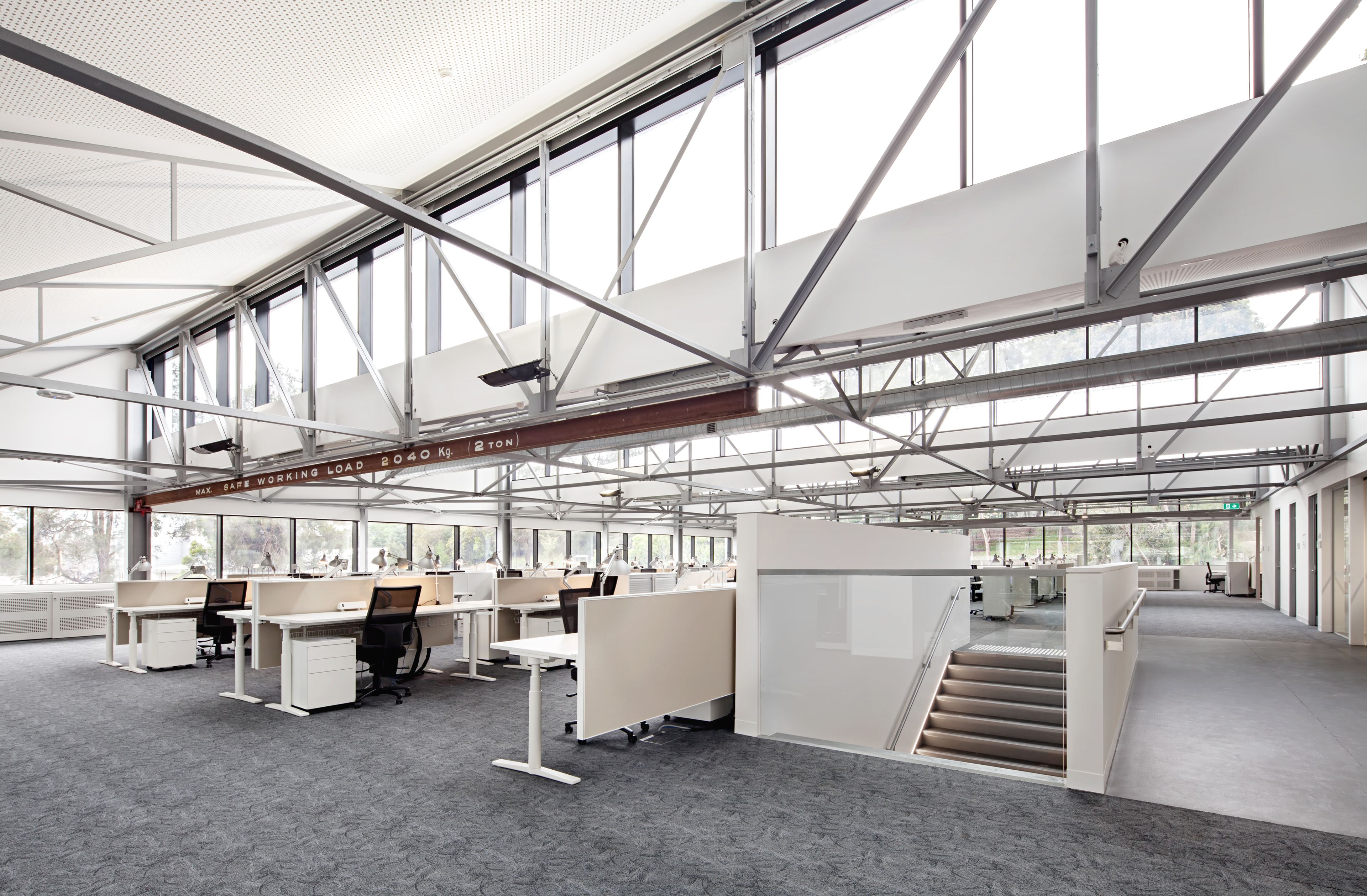 Open-plan workplace at Monash University Building 56, showcasing adaptive reuse, exposed steel structure and contemporary office design.