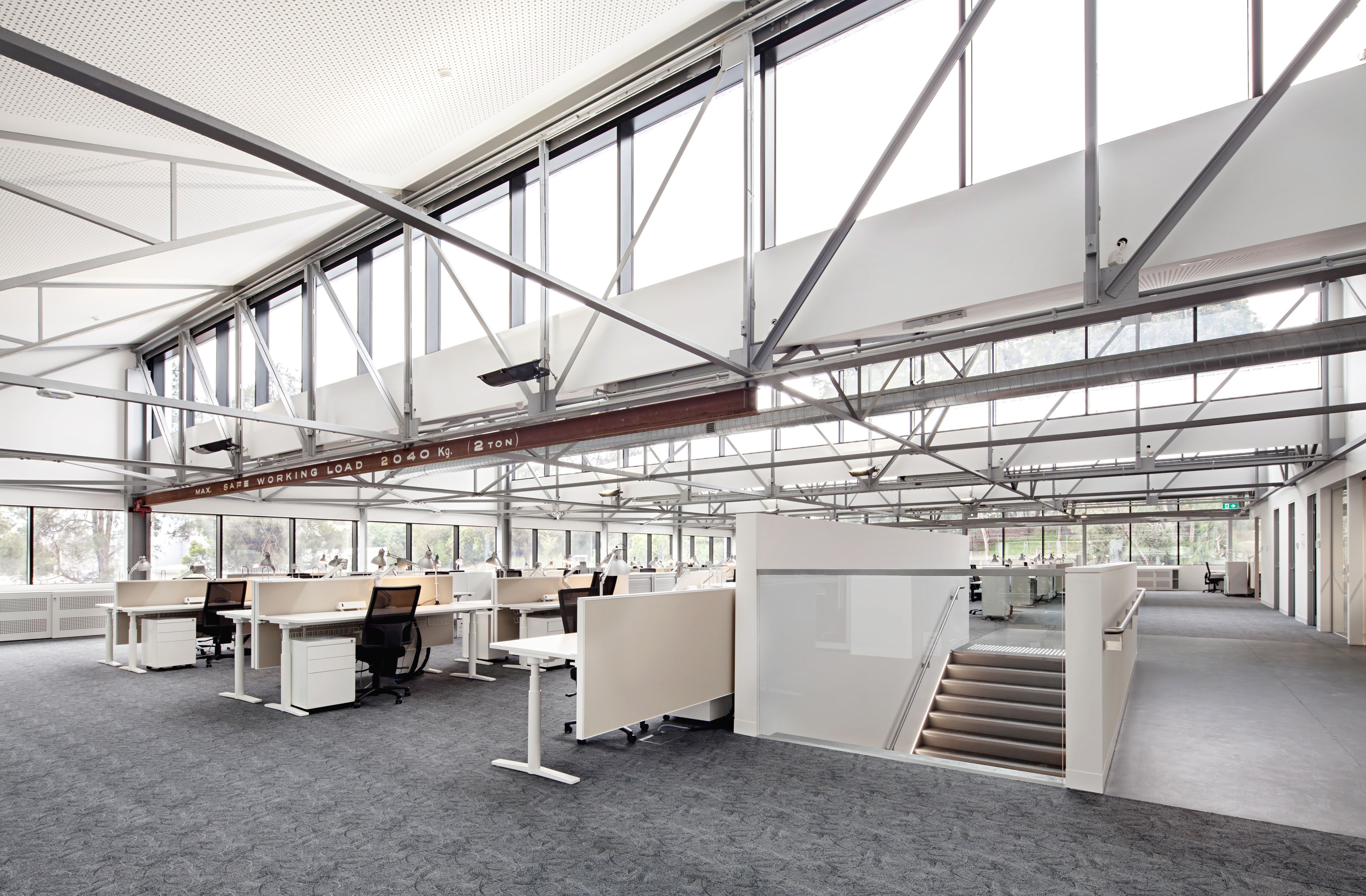 Open-plan workplace at Monash University Building 56, showcasing adaptive reuse, exposed steel structure and contemporary office design.