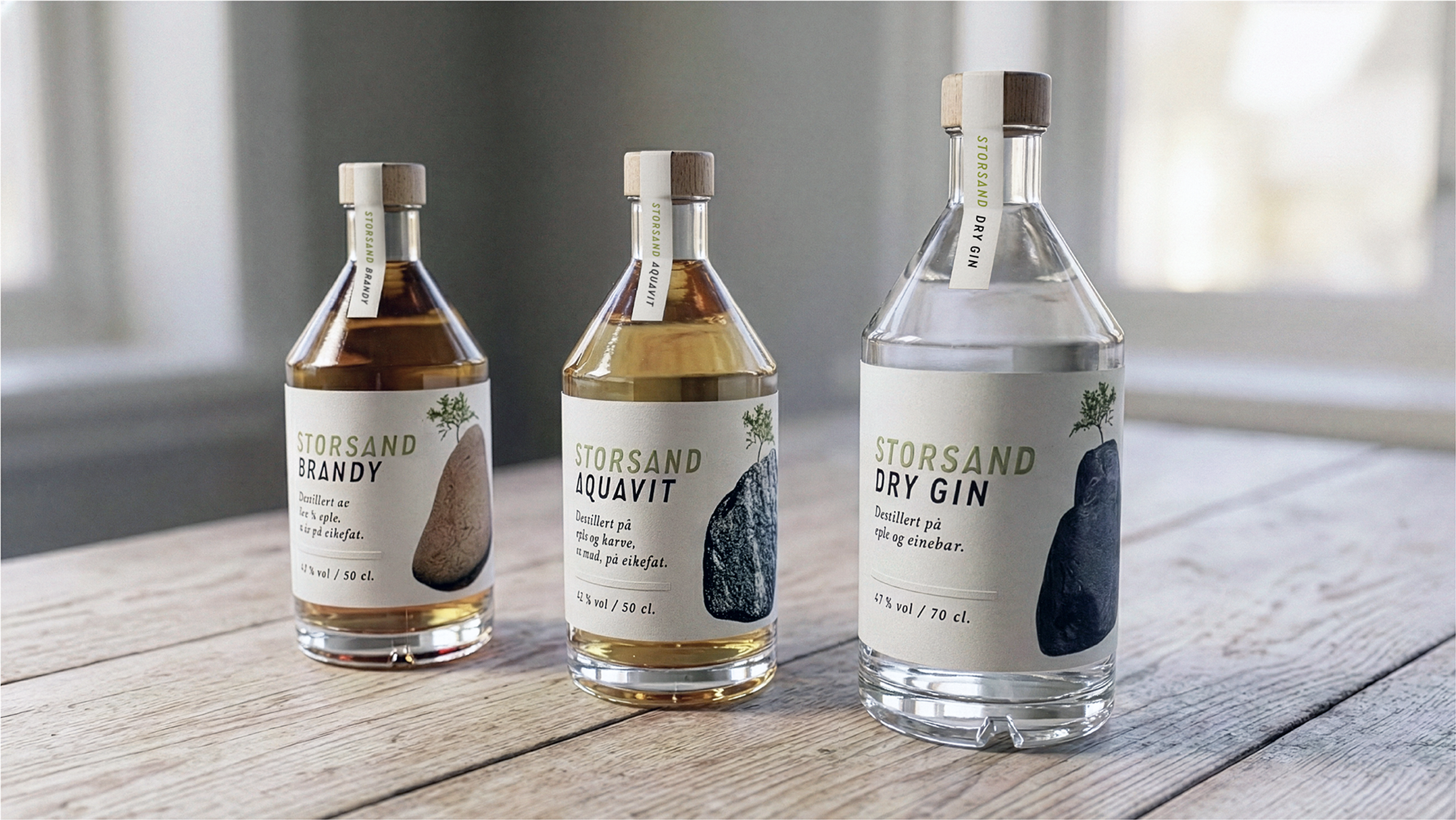 Tre flasker Storsand premiumbrennevin: Brandy, Aquavit og Dry Gin