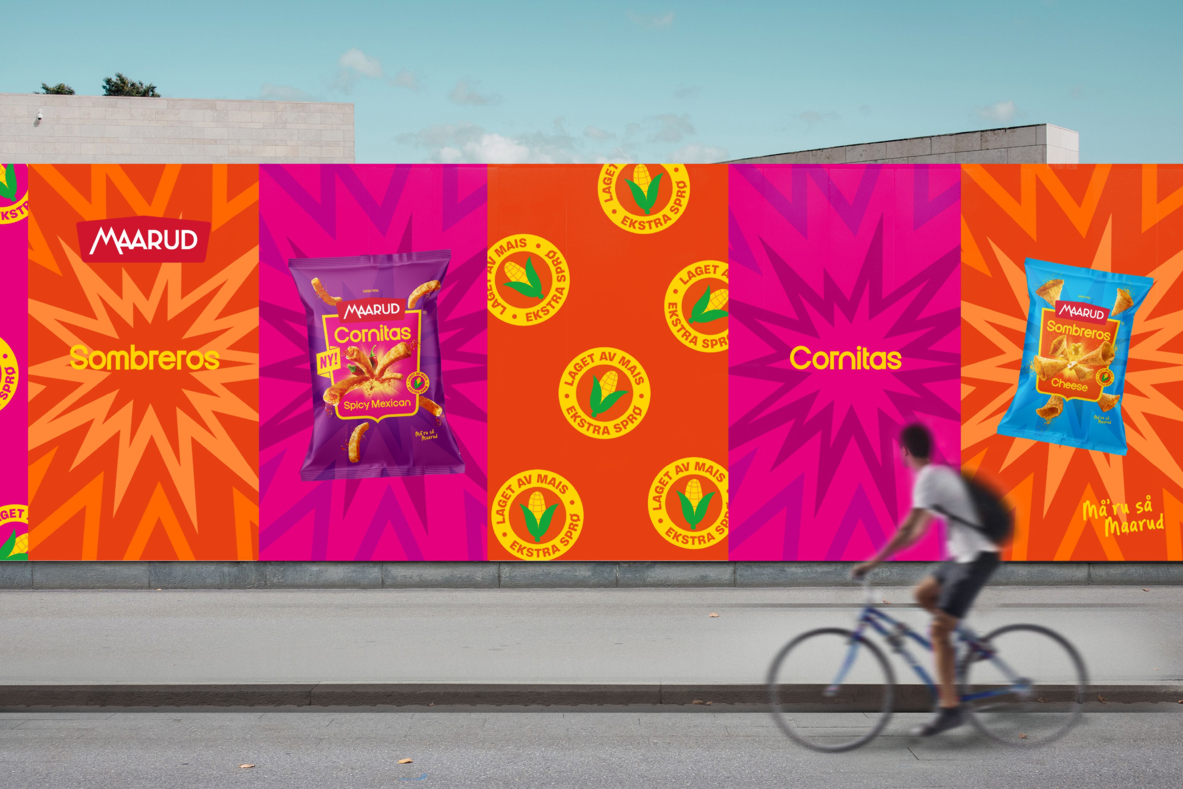 Utendørsvegg i Oslo med Cornitas og Sombreros designet tapesert i friske og sterke farger. I front en syklist som titter på veggen i det han passerer. 