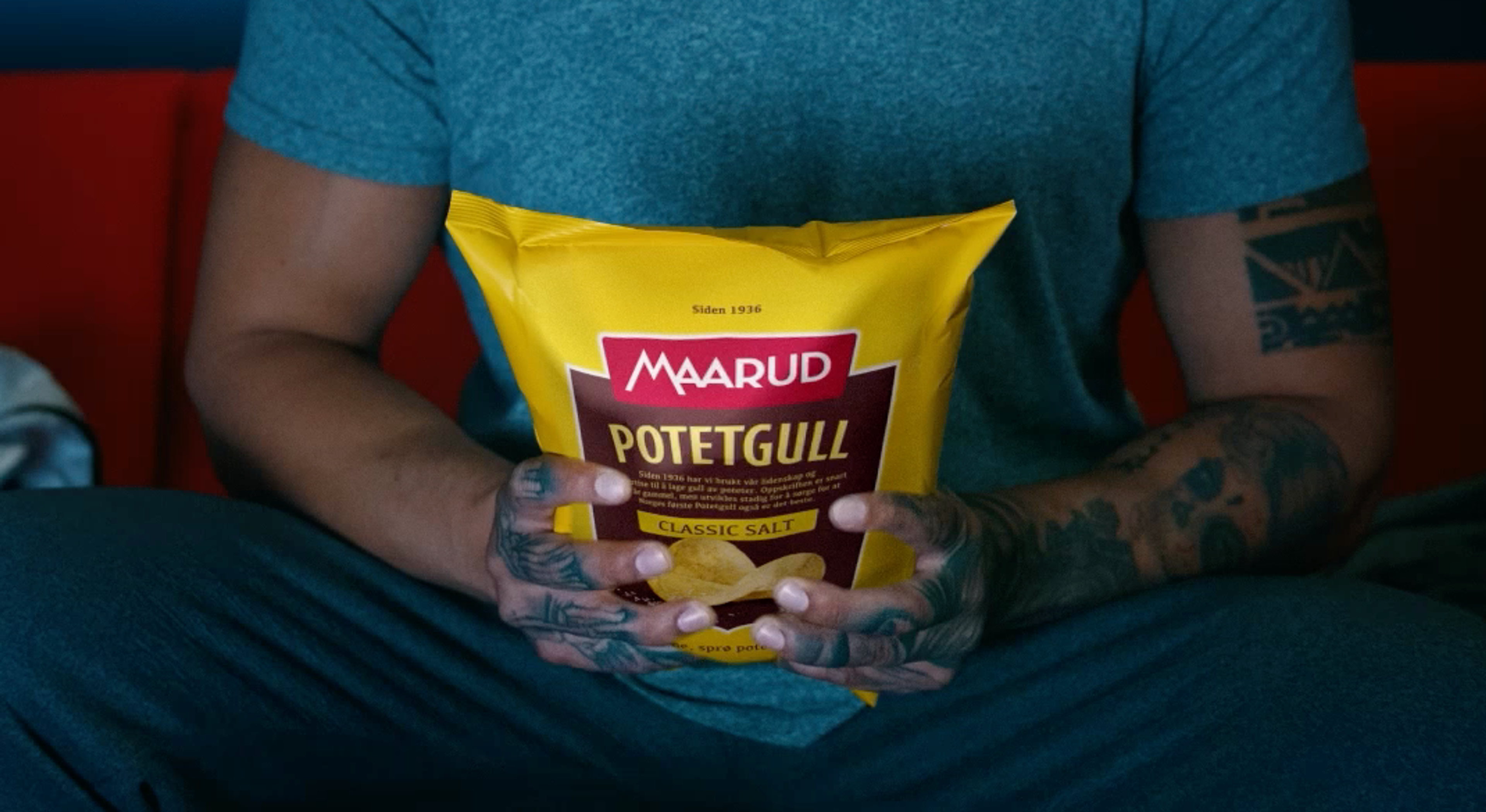 En mann som holder i en gul Maarud Potetgull Salt chips pose