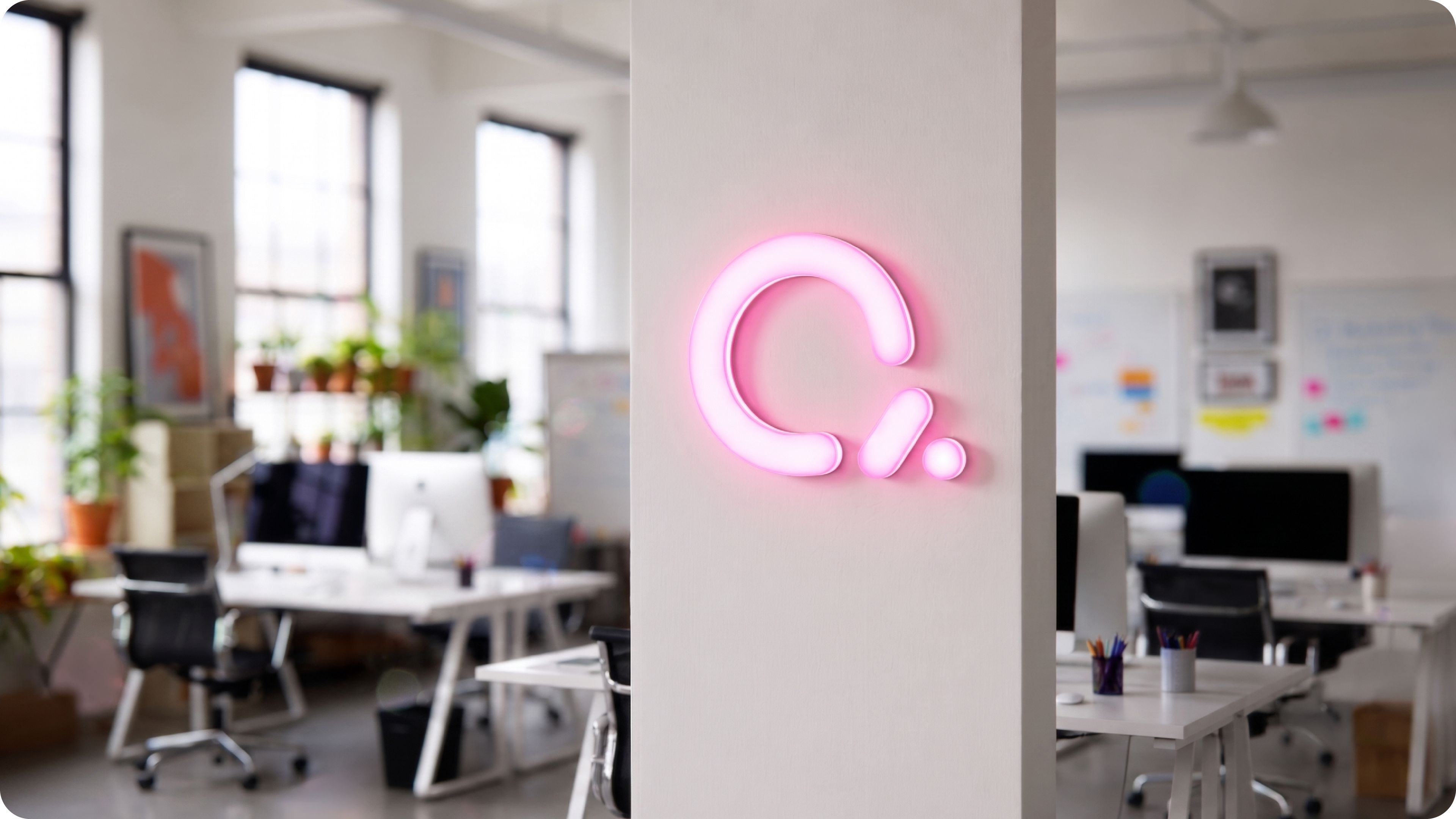 Creative lysskilt i rosa neon på kontorveggen i et åpent kontor landskap.