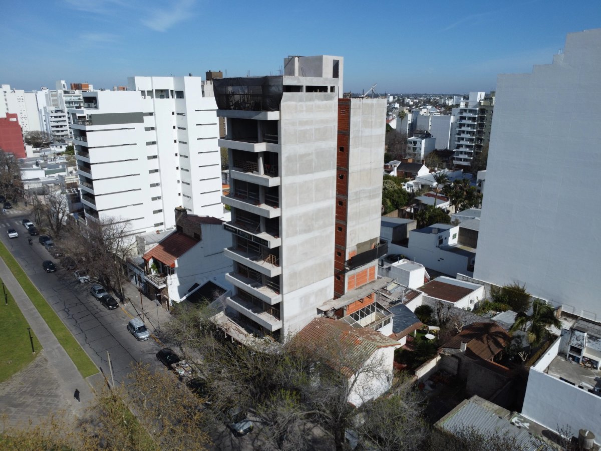 Vista aérea oblicua de Anton Plaza en etapa de construcción, con relación directa al entorno urbano y a la plaza.