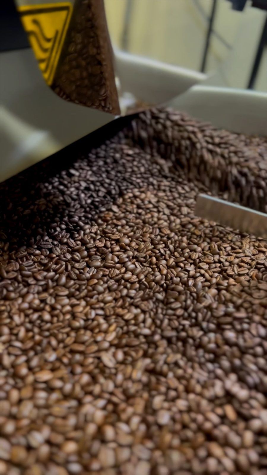 Macro shot of coffee beans pouring into the roaster