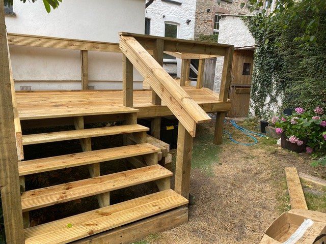 Chunky timber steps and platform behind the cottage