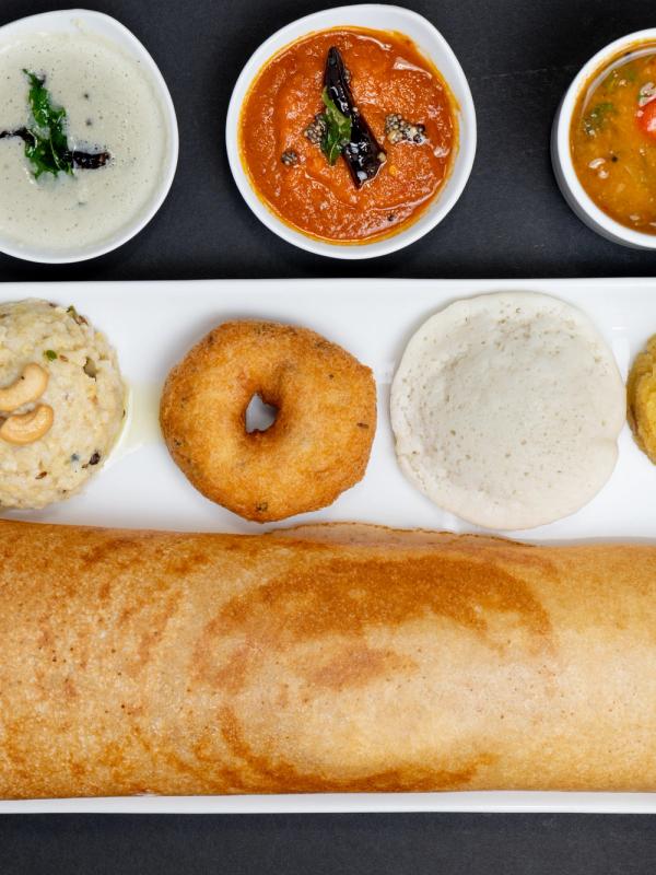 A South Indian mini tiffin platter featuring assorted breakfast favorites served with chutneys and sambar.