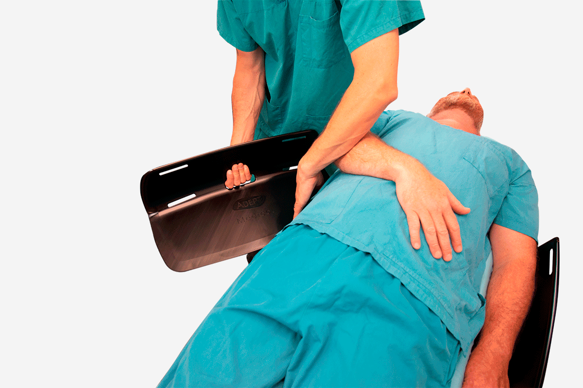 A medical professional uses a transfer board to move a patient.
