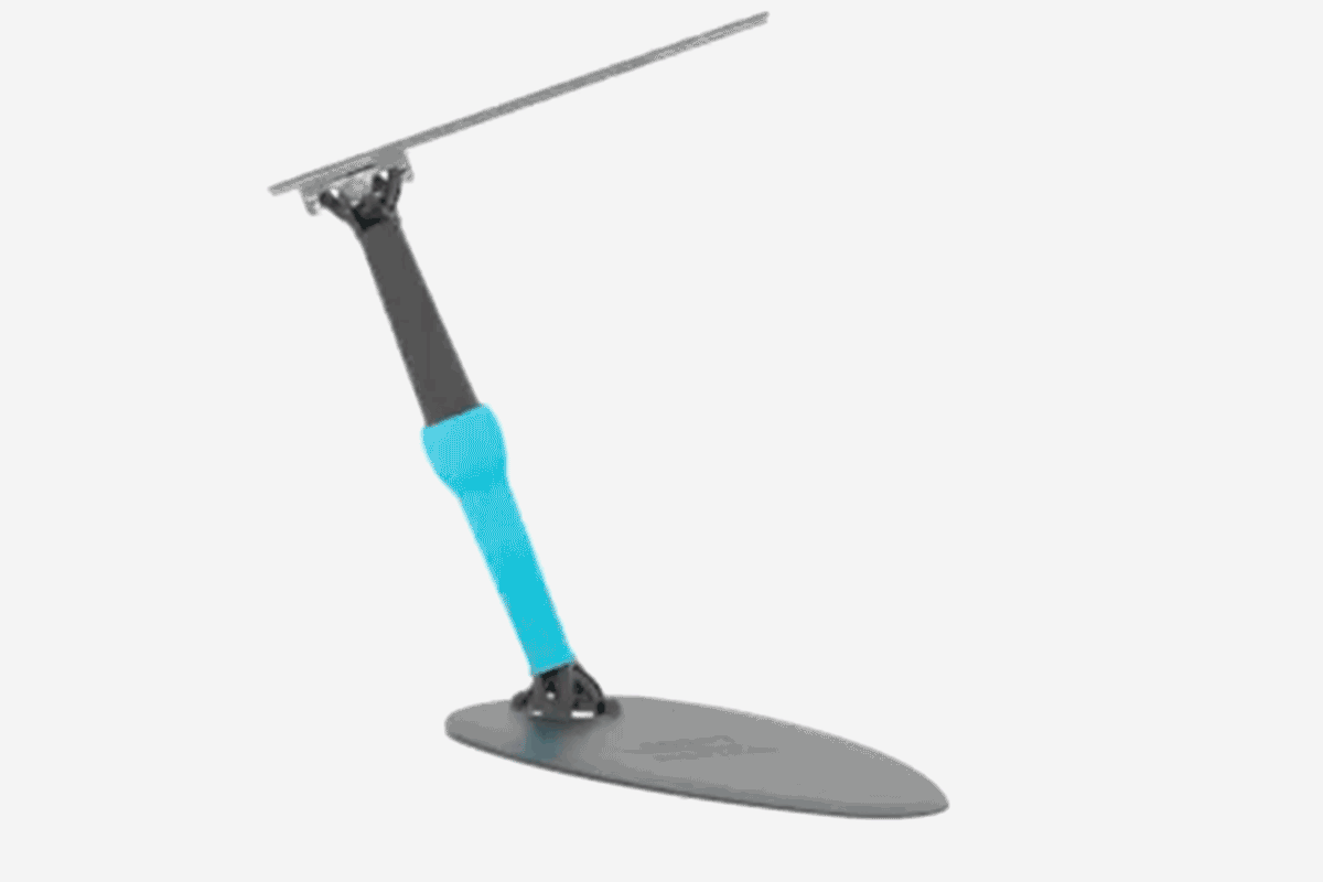 Man lying prone on a medical table, assisted by two medical staff, one holding a reflective board, the other supporting his head on a cushion.