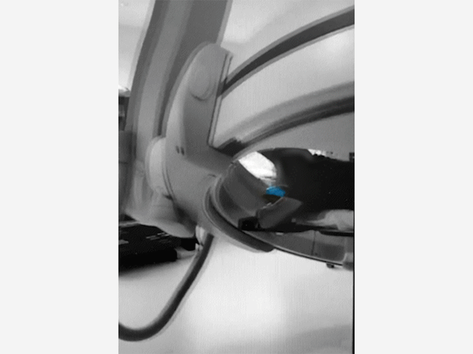 Grayscale close-up of a curved machine part with a blue highlight on a shiny surface.