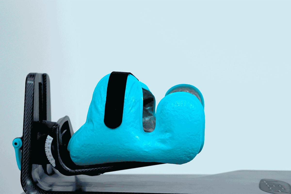 Bright turquoise foot brace with a black strap on an adjustable black frame.