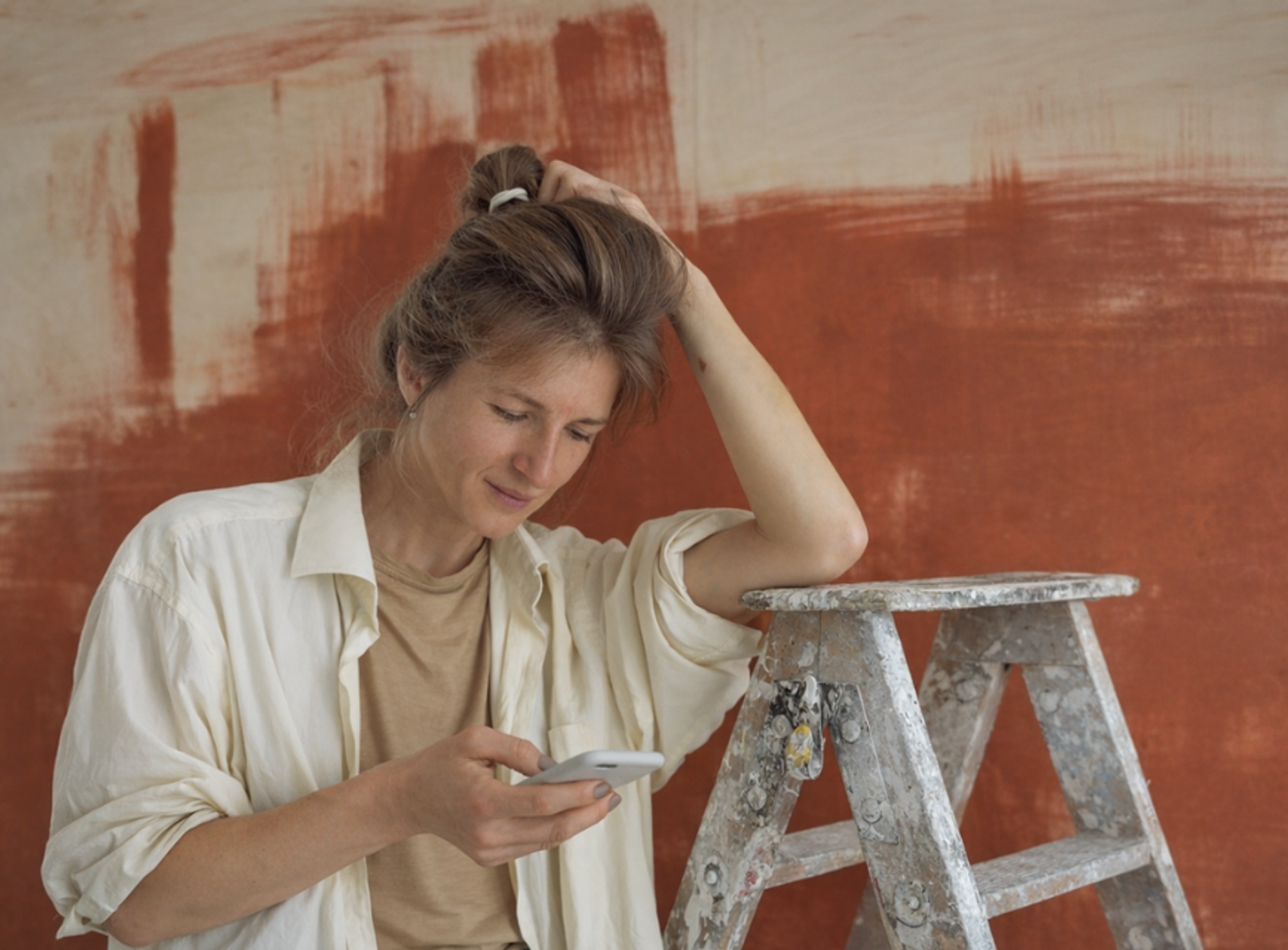 Women with ladder browsing phone