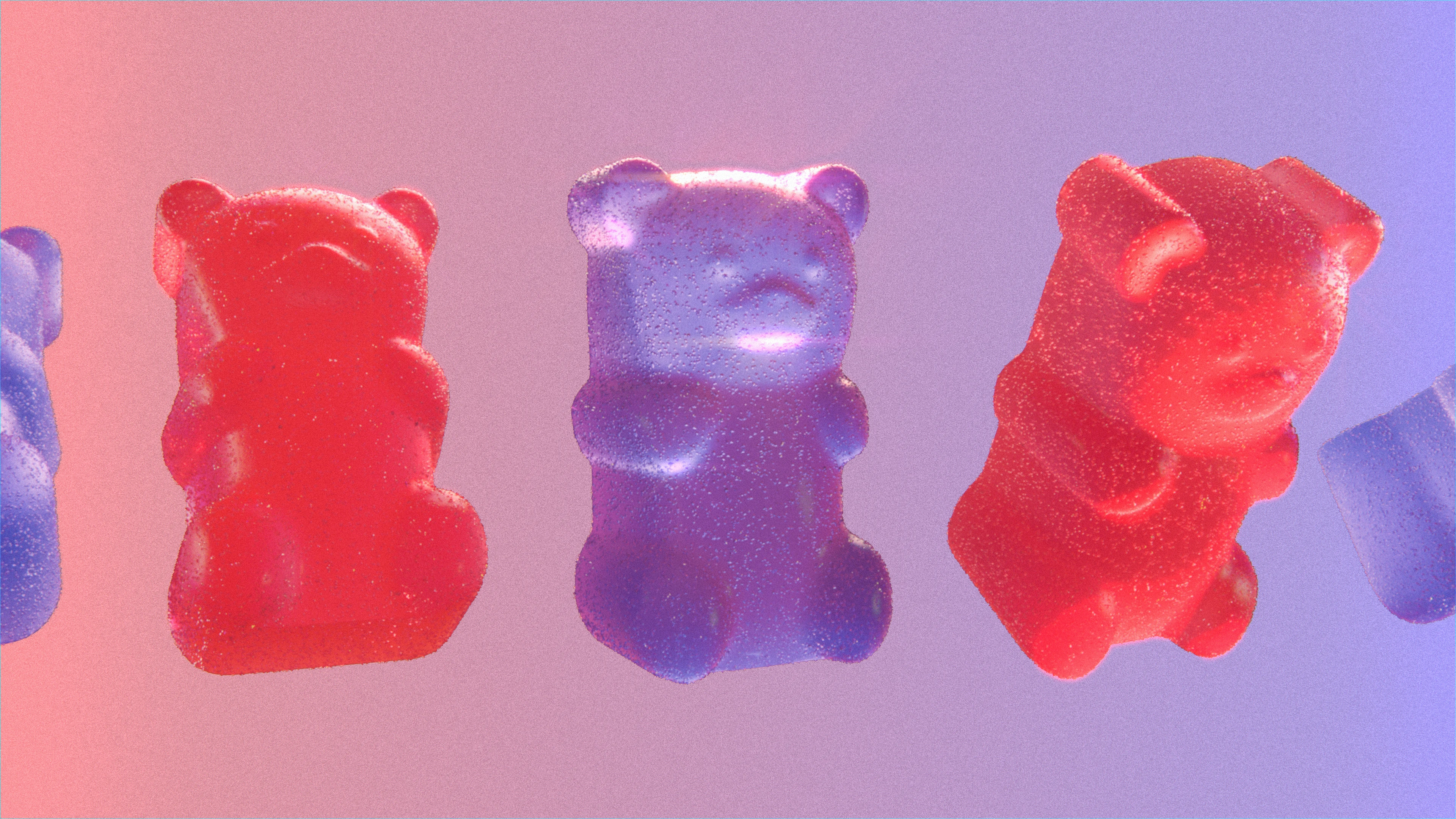 Large red and purple gummy bears in a row against a gradient background