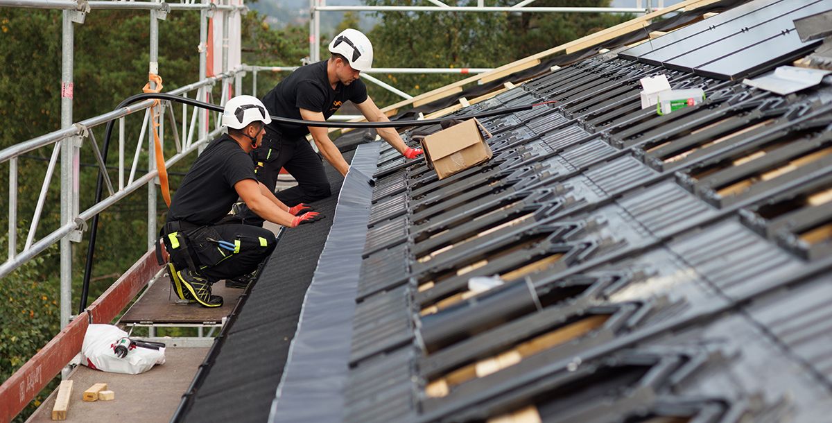 Montører fra Solcellekraft installerer solcellepanel på tak med integrert løsning.