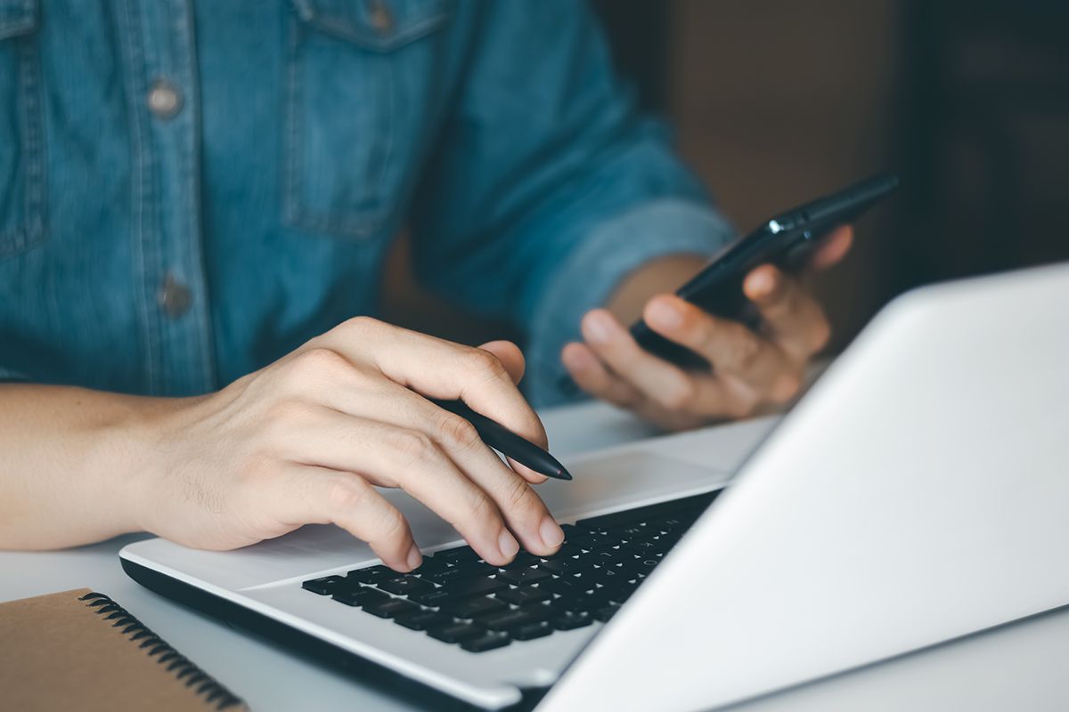 Person som bruker mobil og laptop for å sende en henvendelse om solceller