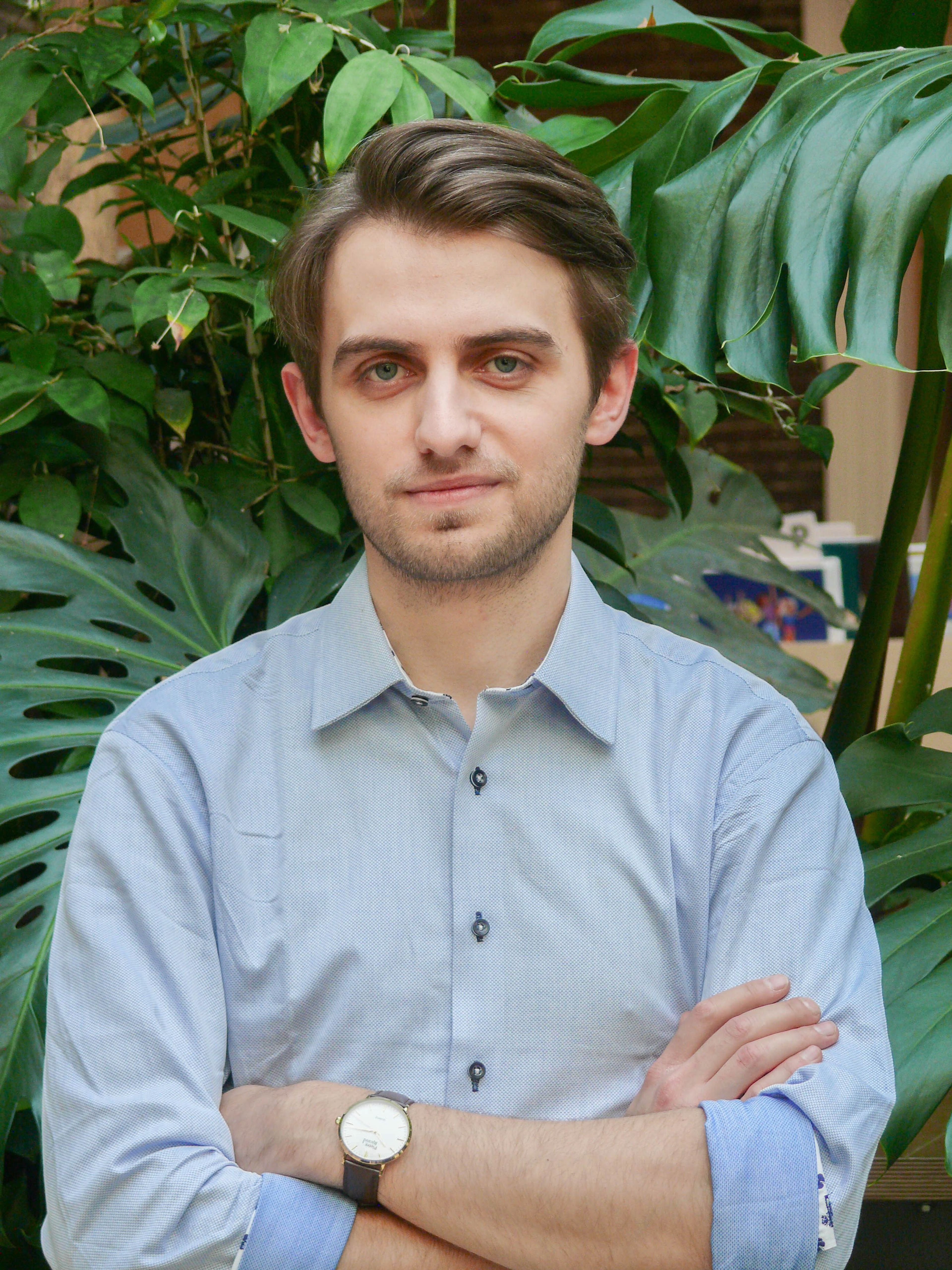 Portrait of Borys Kapica standing in front of plants
