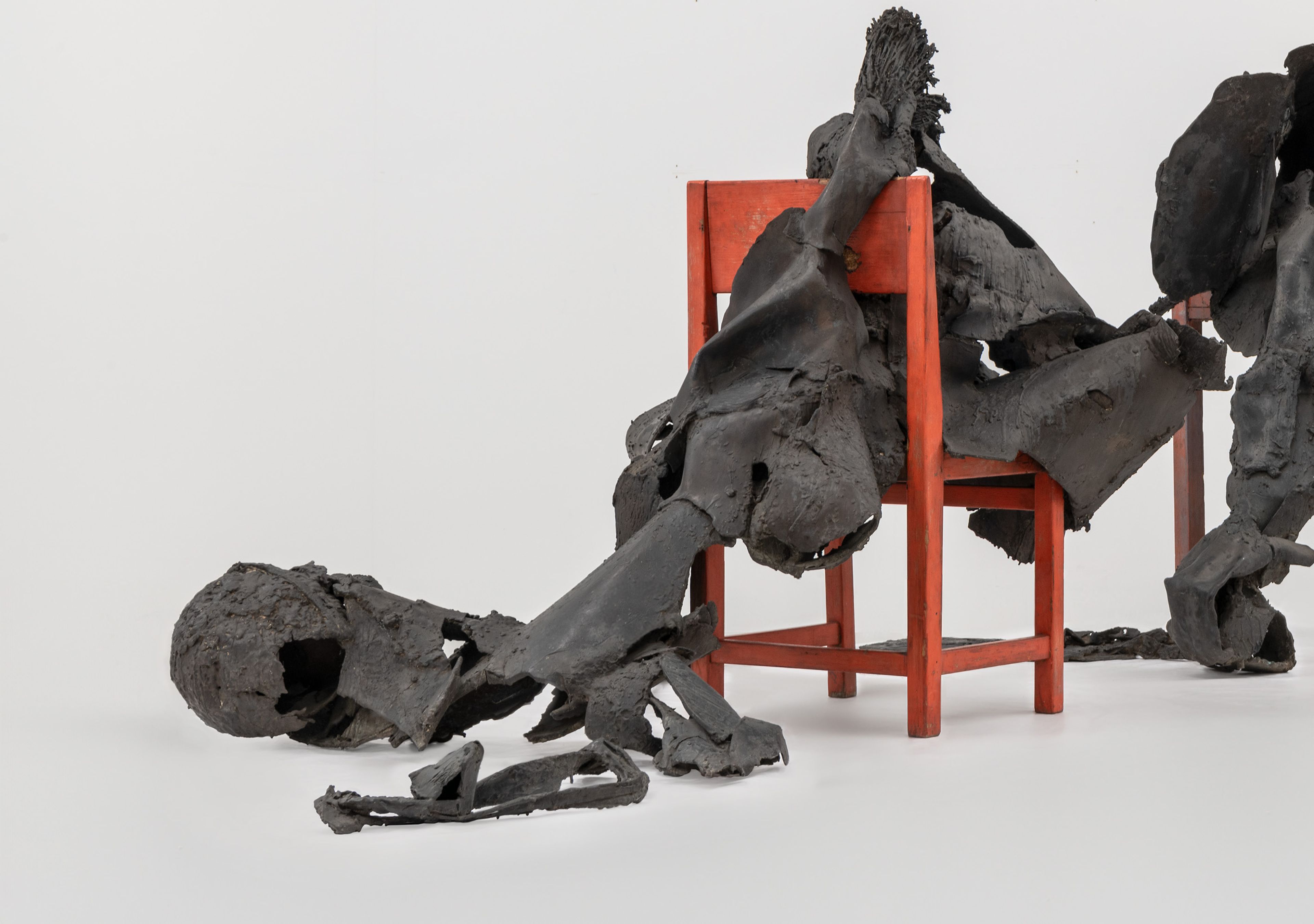 Wessel Couzijn, _Rendez-vous van tafel en stoel_, 1964-1965 Bronzen vormen die lijken op een mens liggend op een halve tafel en een stoel