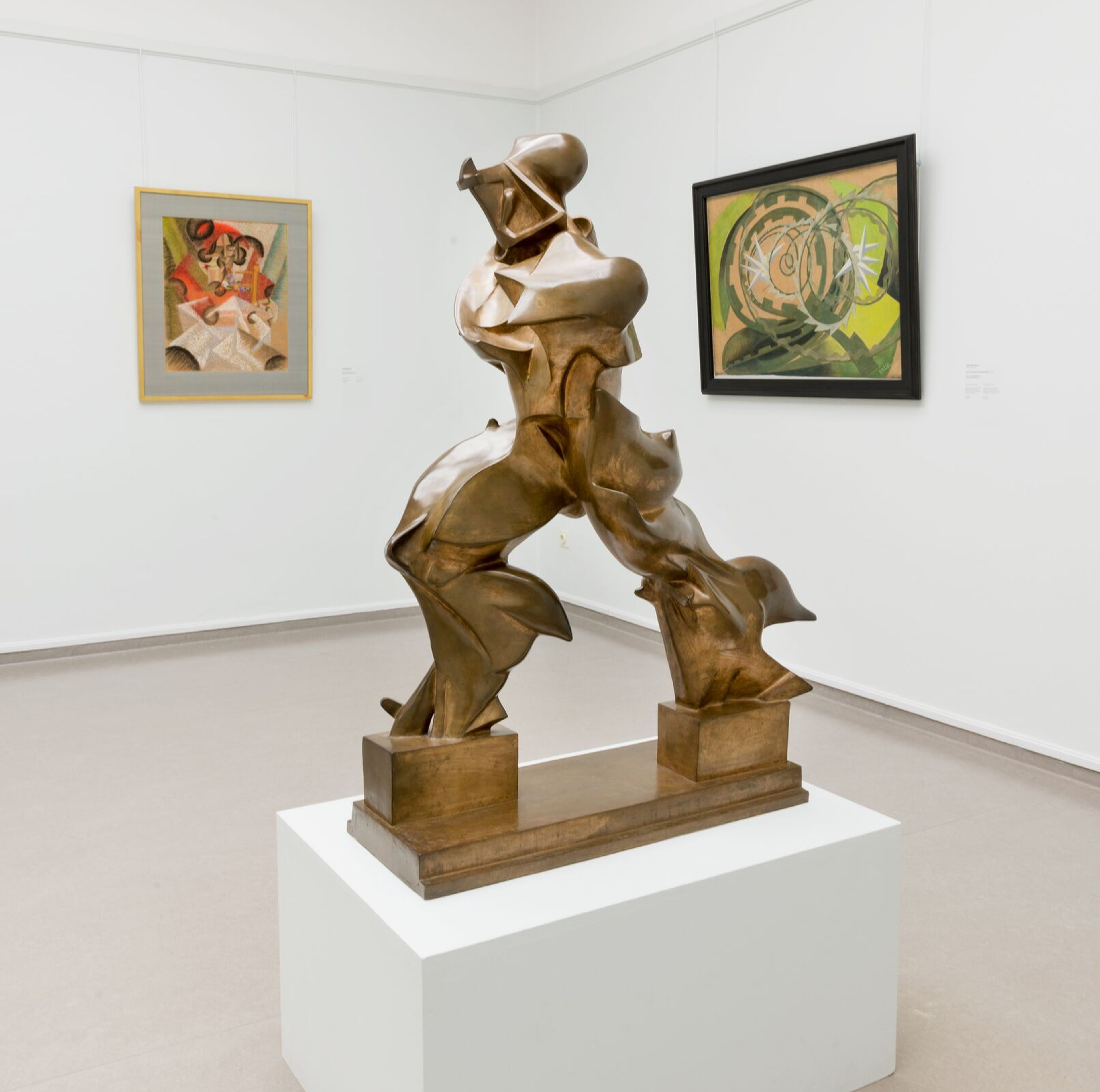 Umberto Boccioni, _Forme uniche della continuità nello spazio_, 1913 Bronzen abstract beeld van een menselijke figuur in een dynamische, voorovergebogen houding. Het sculptuur bestaat uit hoekige, gefragmenteerde vormen en staat op een rechthoekige sokkel tegen een neutrale achtergrond.
