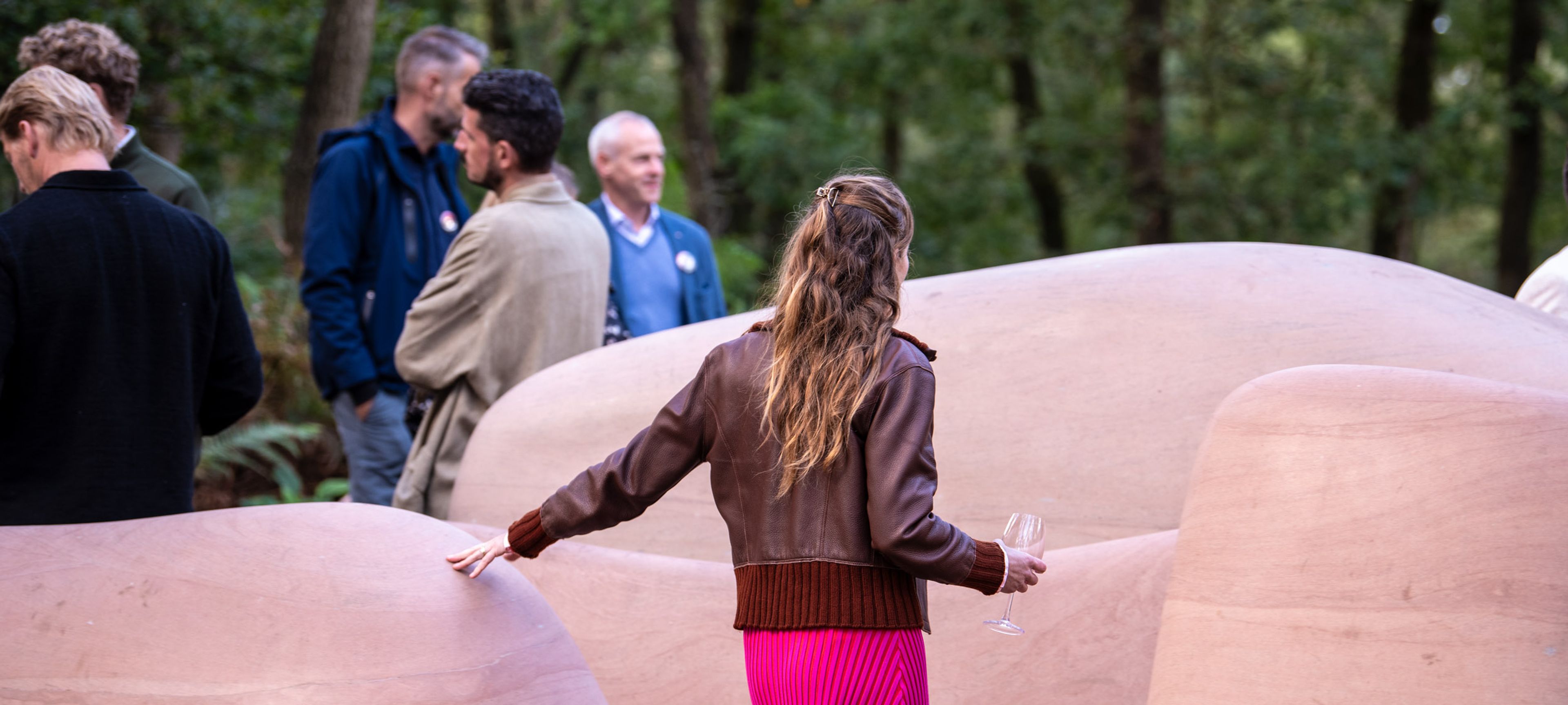 Bezoeker loopt tussen de grote ronde sculpturen van _Rocky Lumps II_ in de beeldentuin van het museum, tijdens een tuinfeest.