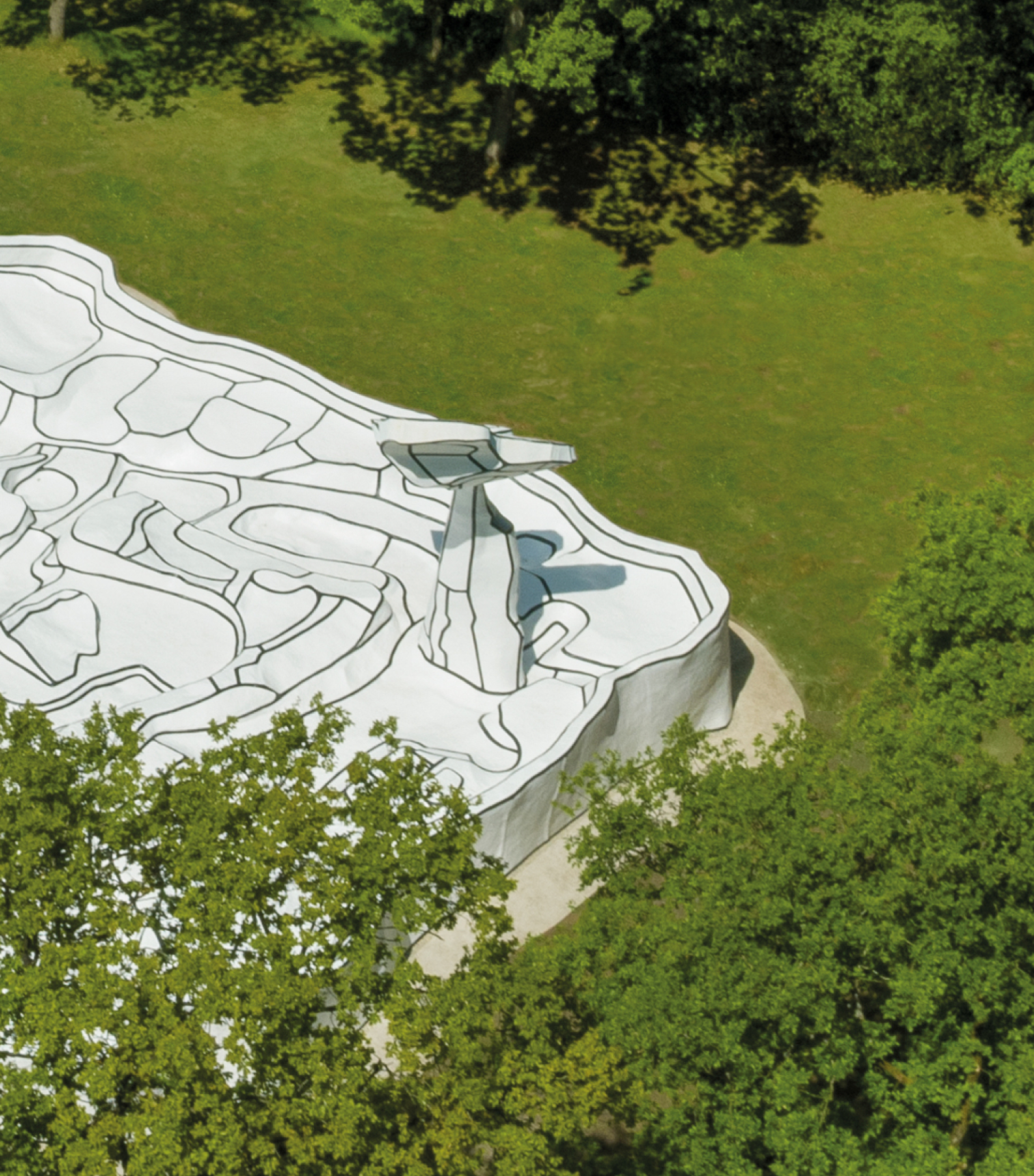 Dronefoto van het kunstwerk Jardin d'émail, een zwart-witte ondergrond op een groen grasveld met bomen eromheen