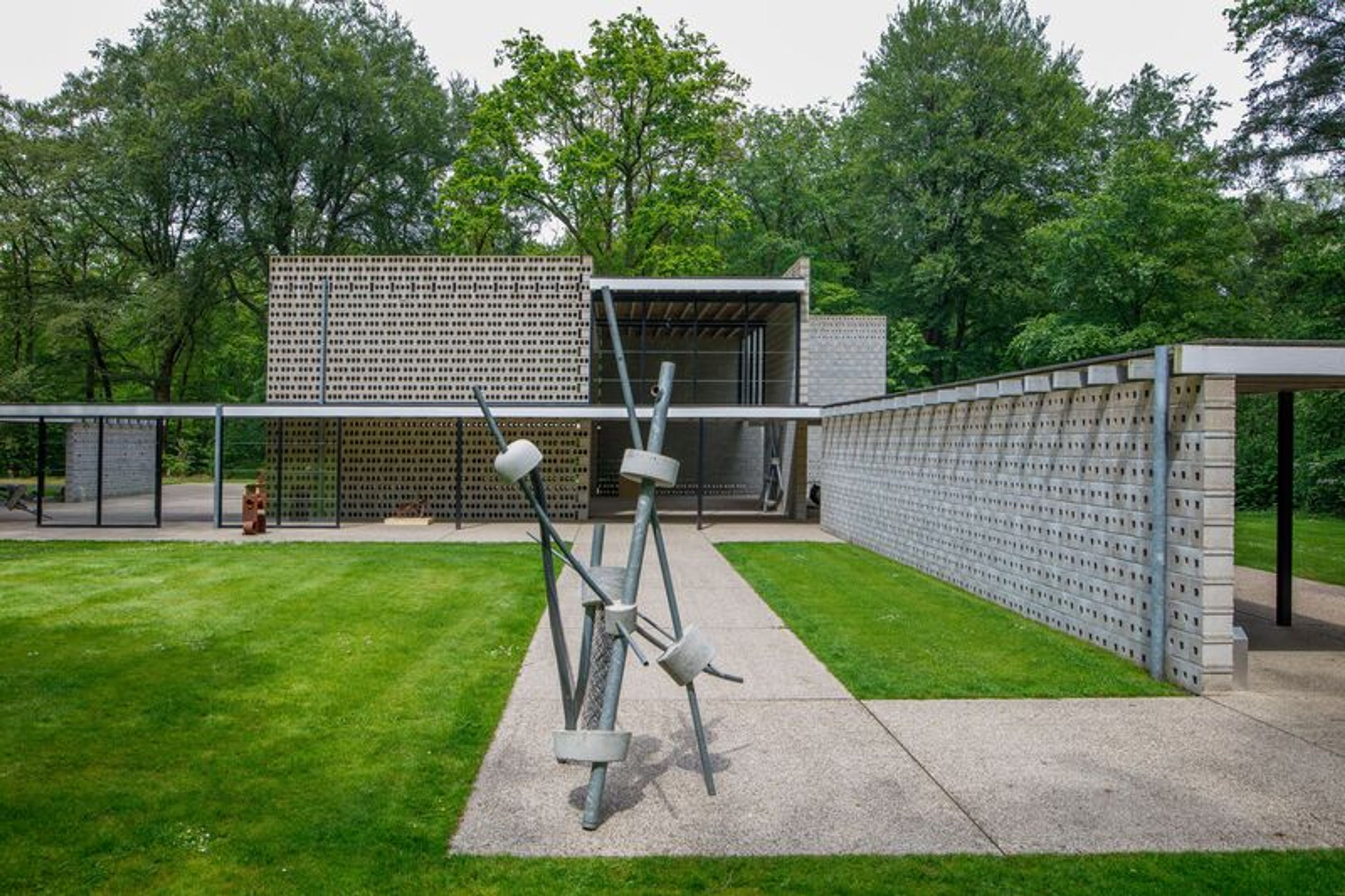 Ruud Kuijer, _Sprong (nr. 228)_, 1999, foto: Rob Versluys Foto van een aantal beelden in staal in een modern paviljoen in een parkachtige omgeving