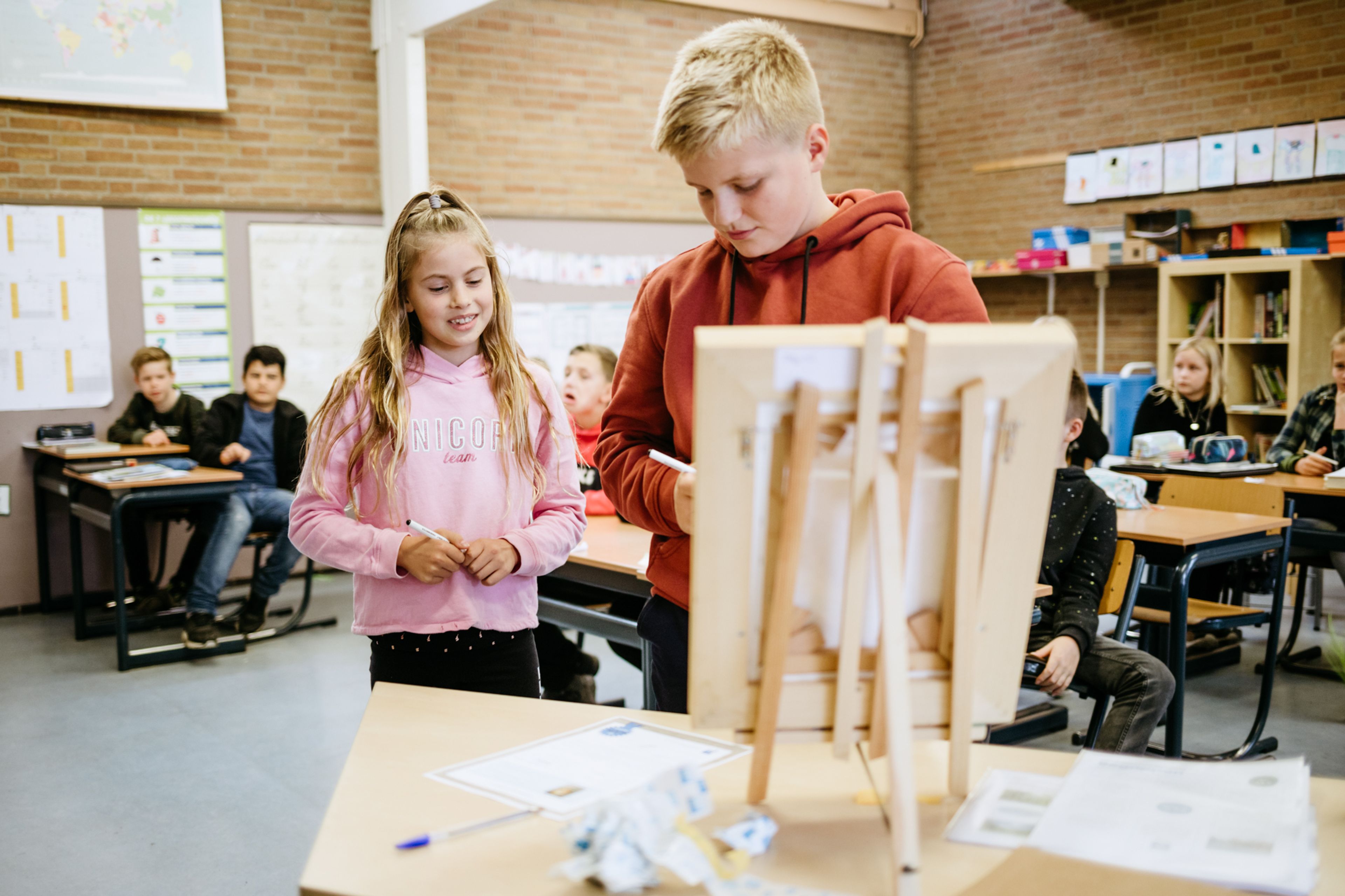 Twee leerlingen staan bij een schildersezel voor in de klas