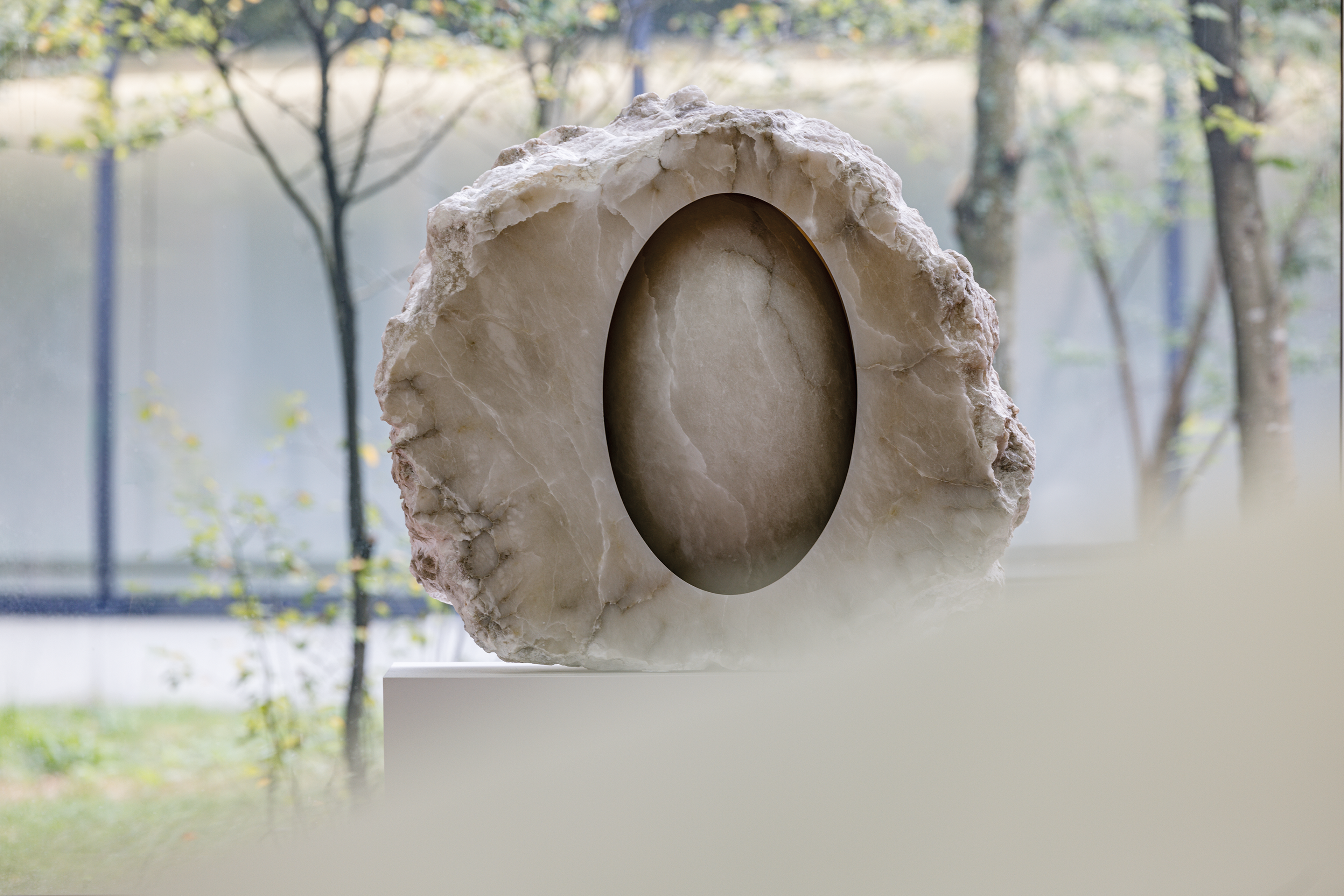 Anish Kapoor, _Untitled_, 2018 Foto van een abstracte beeldhouwwerk bestaande uit een ruwe, ronde steen met een glad, ovale uitsparing in het midden.