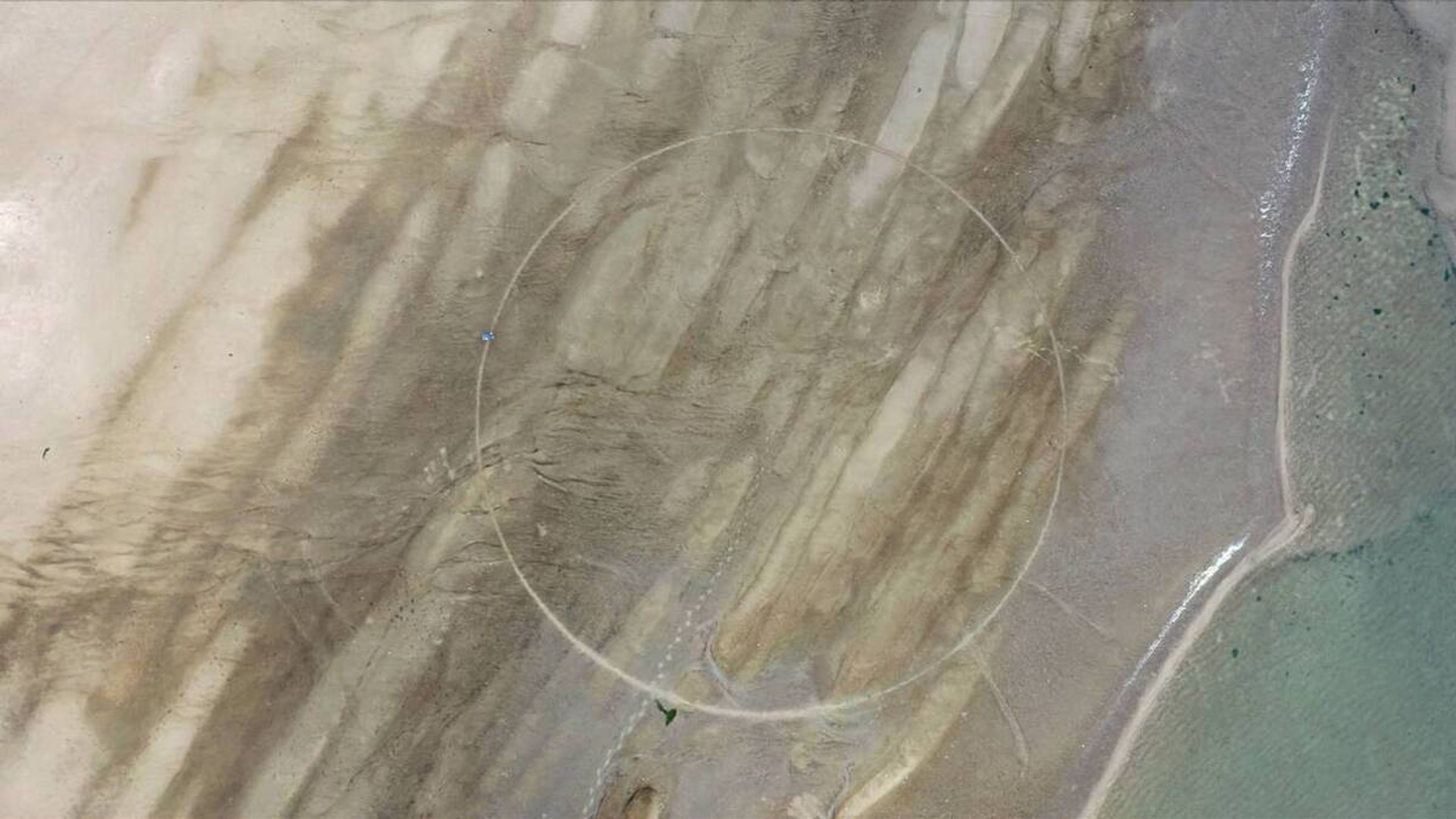 Jeroen Jongeleen, _Practice for Elon’s Mars_, 2020 Luchtfoto van een landschap met zand en water met een cirkel in het midden