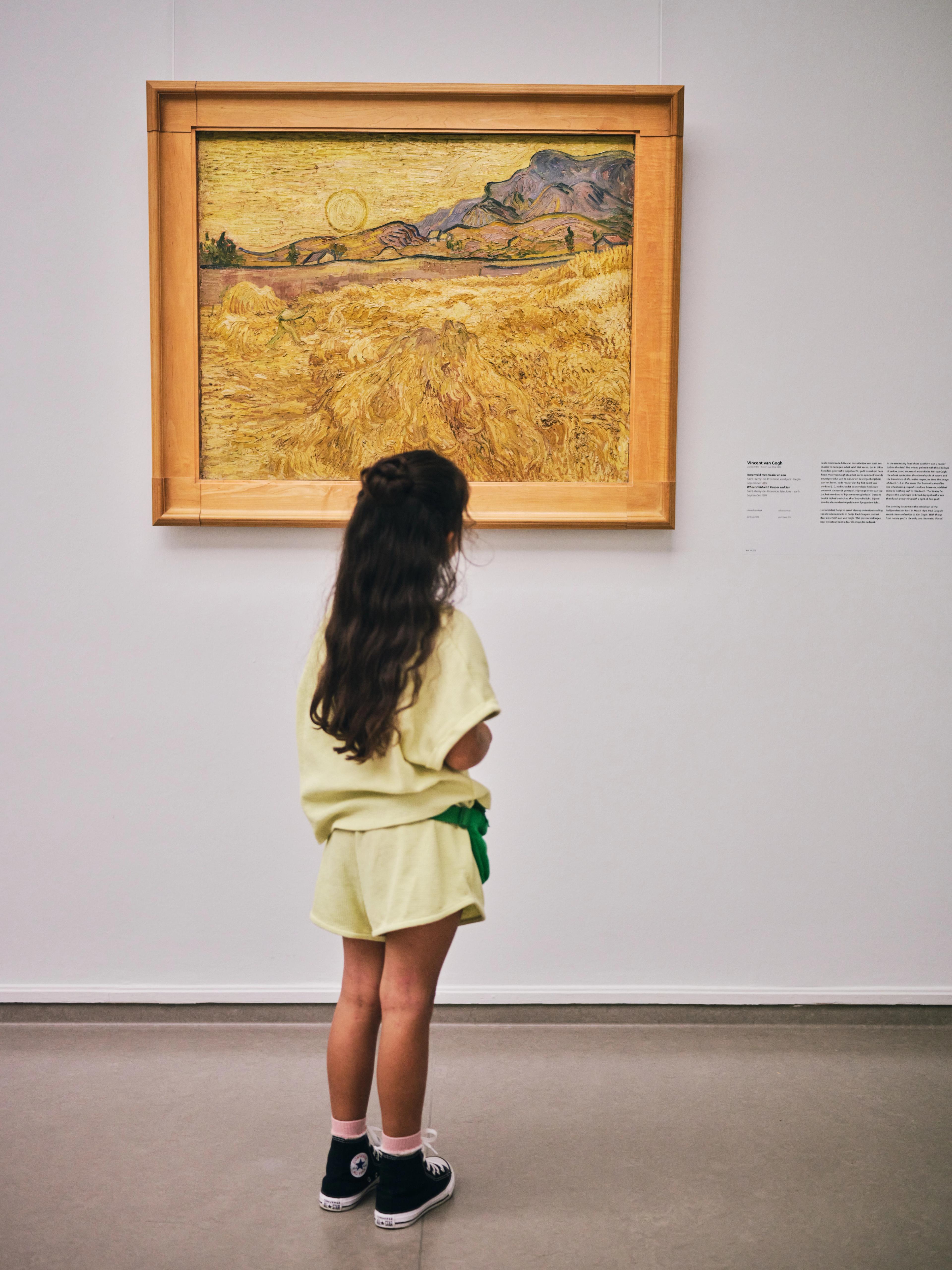 Kind kijkt naar een geel schilderij van Vincent van Gogh, met een veld