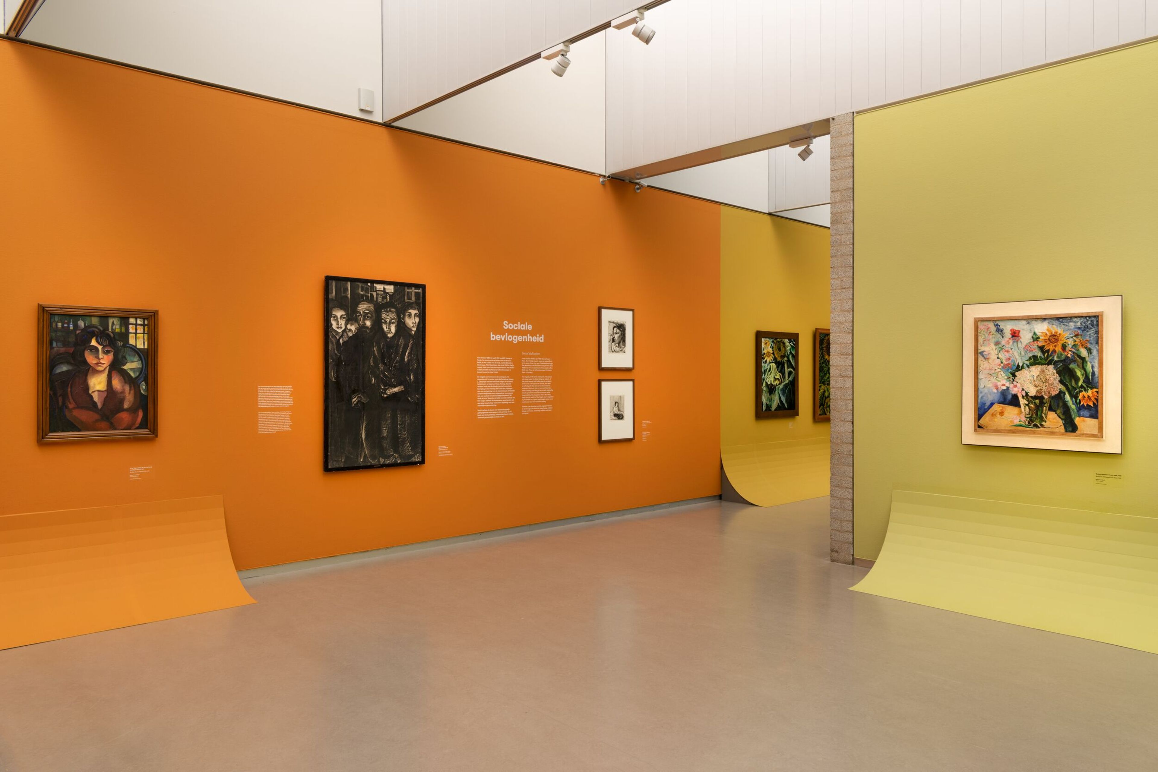 Zaaloverzicht _Charley Toorop. Liefde voor Van Gogh_ Foto van een tentoonstelling met muren in oranje en geel, waarop diverse schilderijen zijn tentoongesteld.