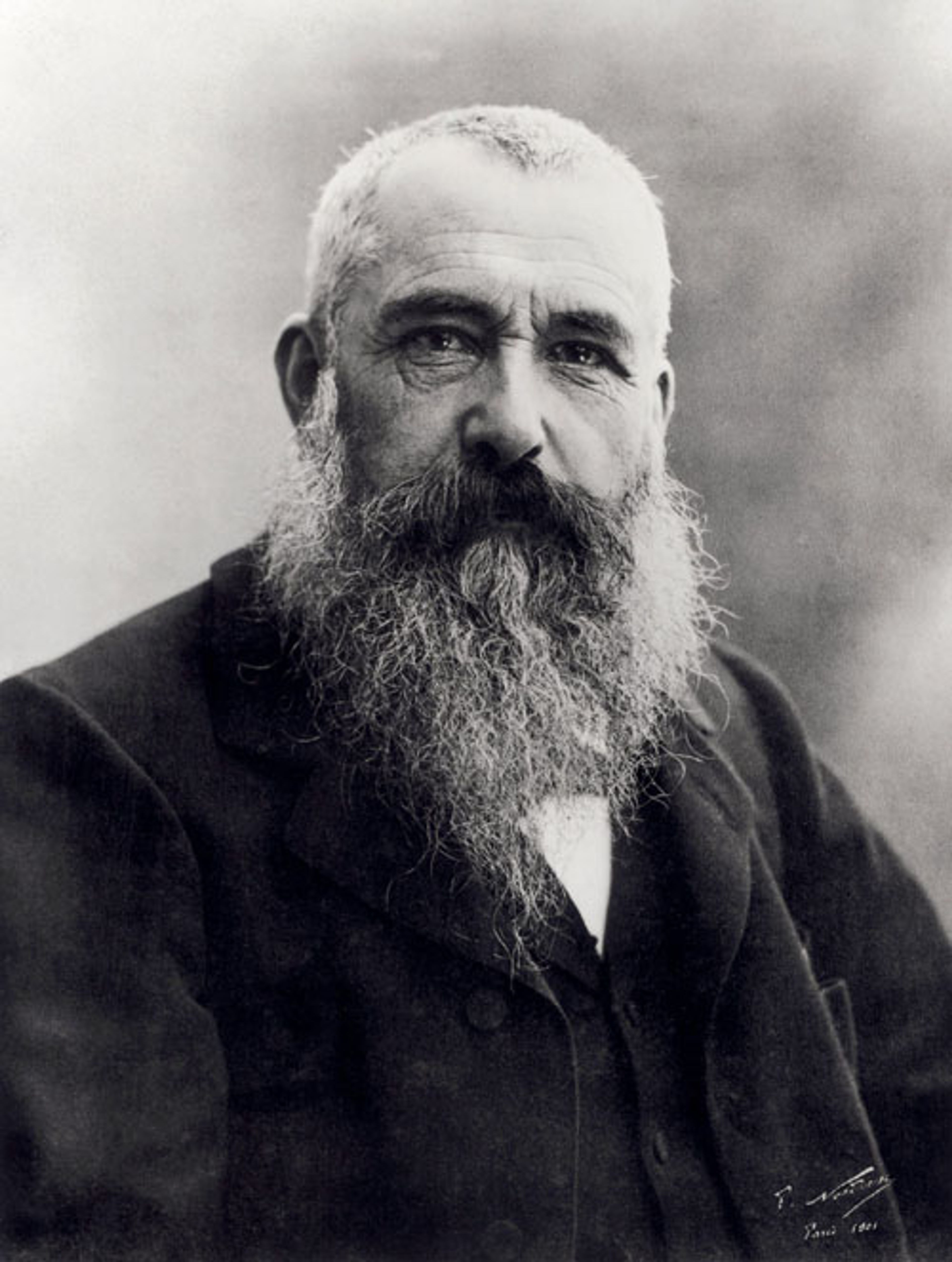 Zwart-witfoto van Claude Monet. Een oudere man met een lange, volle baard en een donker pak. Klassiek portret met zachte achtergrond en gedetailleerde textuur in kleding en baard.