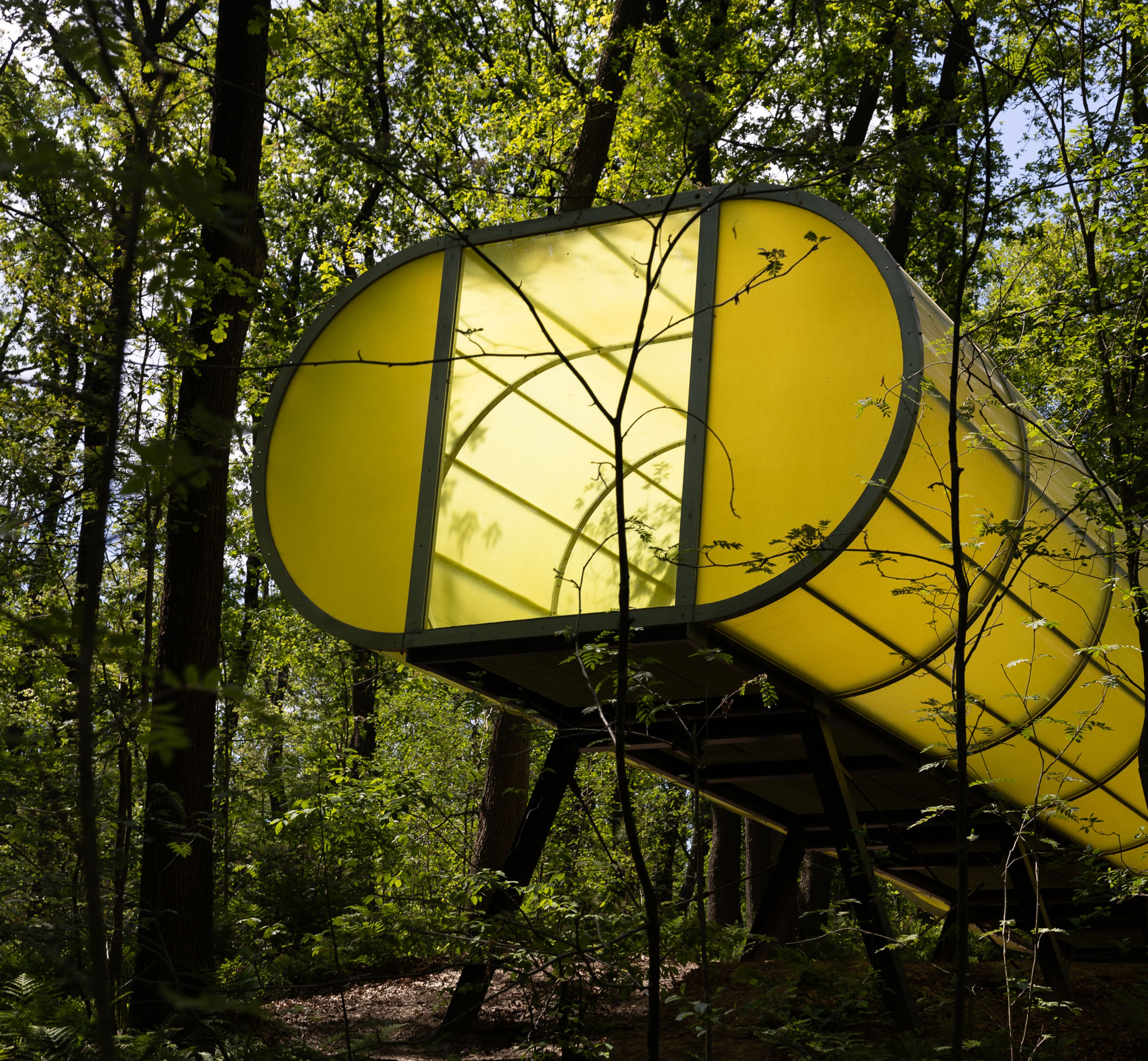 Hermann Maier Neustadt, _WD-Spiral Part One CINEMA_, 2001 Photo of a green tube emerging from a landscape of trees. The final section of the tube is supported by metal supports, and at the end there is an opening for looking outside.