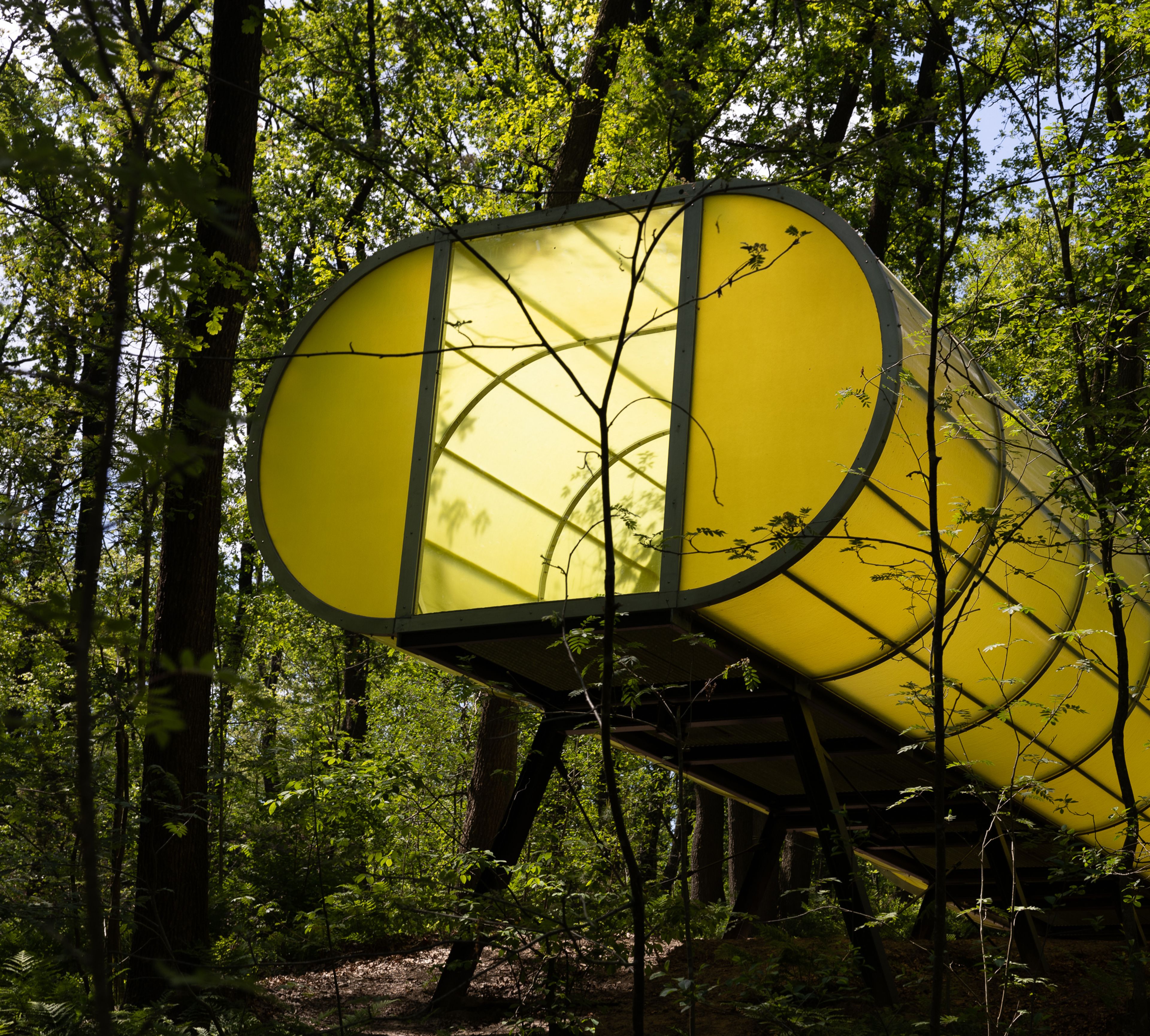 Hermann Maier Neustadt, _WD-Spiral Part One CINEMA_, 2001 Foto van een groen soort buis die uit een landschap van bomen steekt, het laatste deel van de buis steunt op metalen dragers, aan het eind een opening om naar buiten te kijken