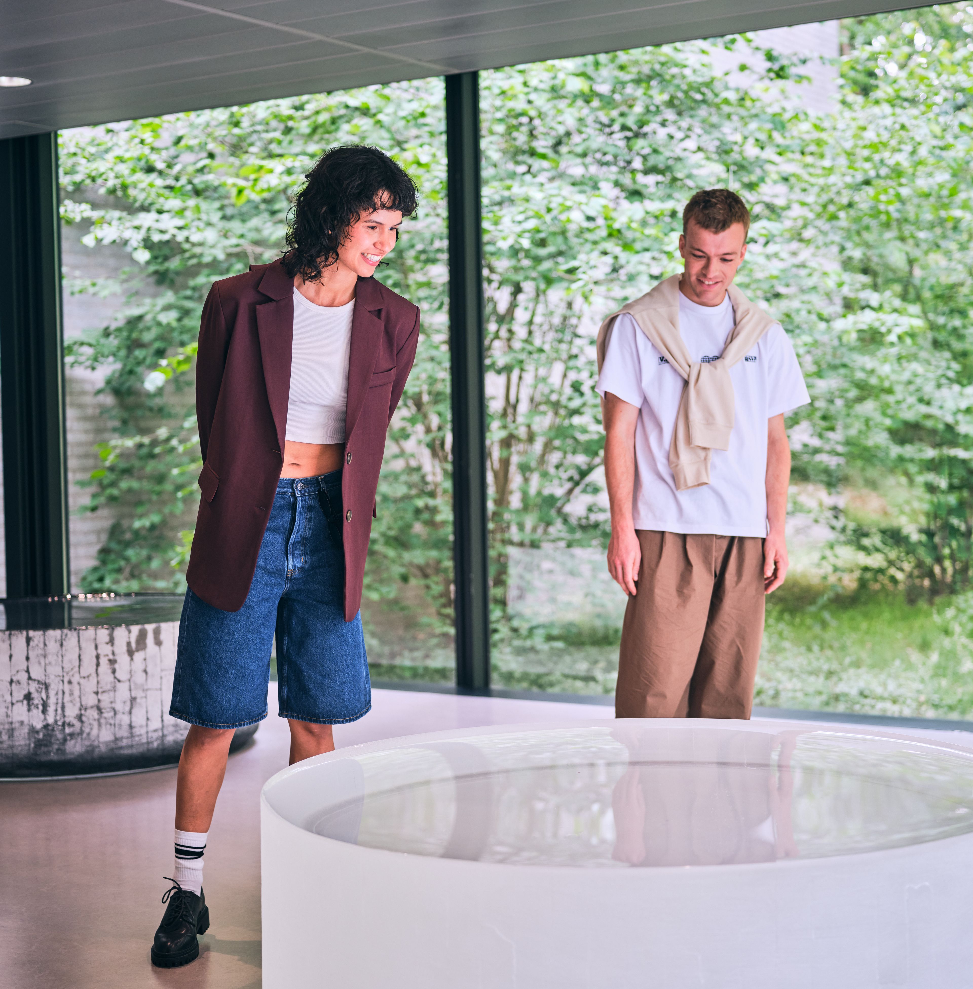 Twee bezoekers in een ruimte met uitzicht op groen, bij het kunstwerk 'Opposites of White'  van Roni Horn