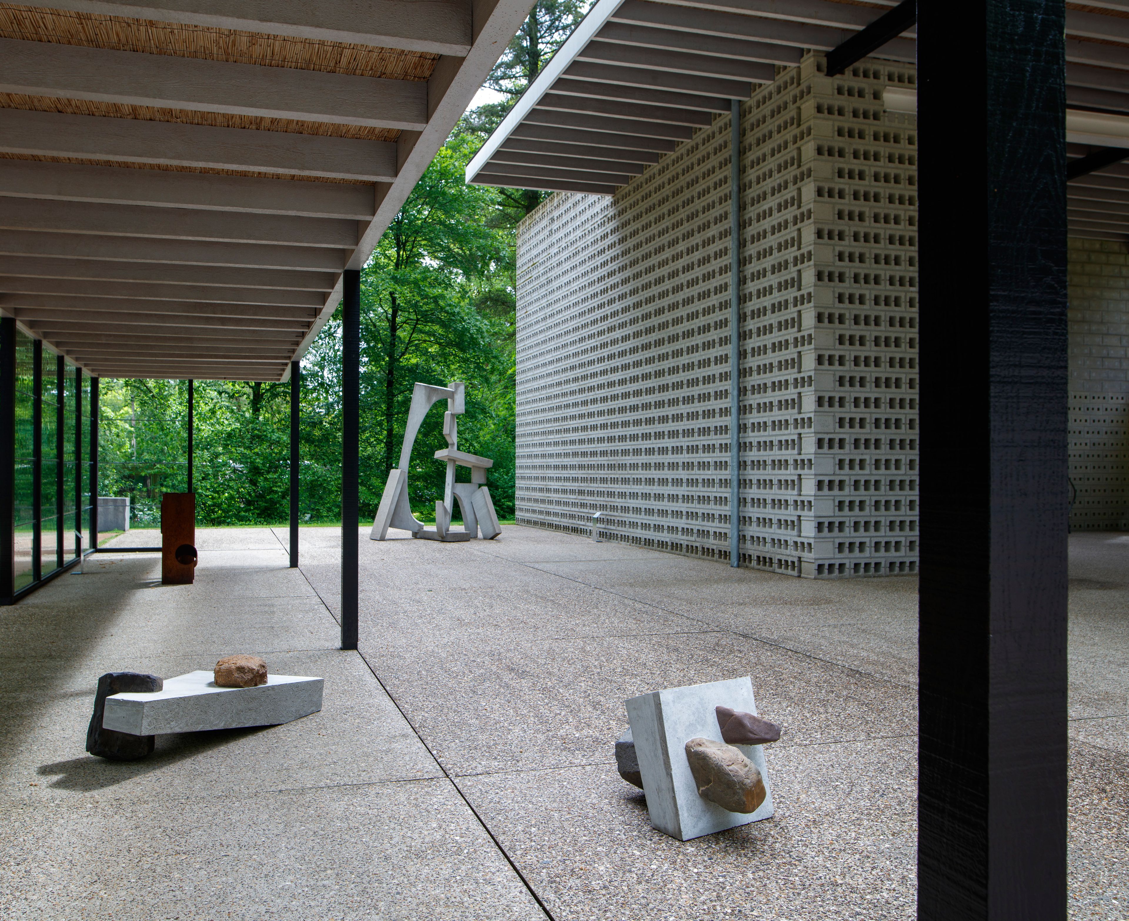 Ruud Kuijer in het Rietveldpaviljoen, foto: Rob Versluys Foto van een aantal beelden in staal in een modern paviljoen in een parkachtige omgeving. De beelden hebben grillige vormen
